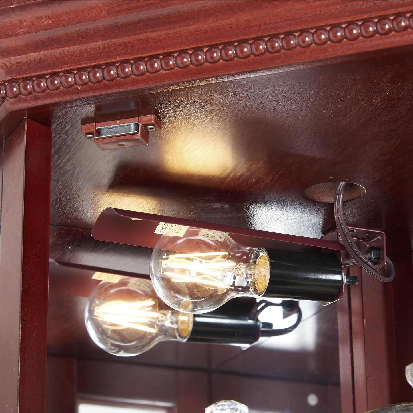 Two Edison style LED bulbs illuminate a dark wood cabinet interior
