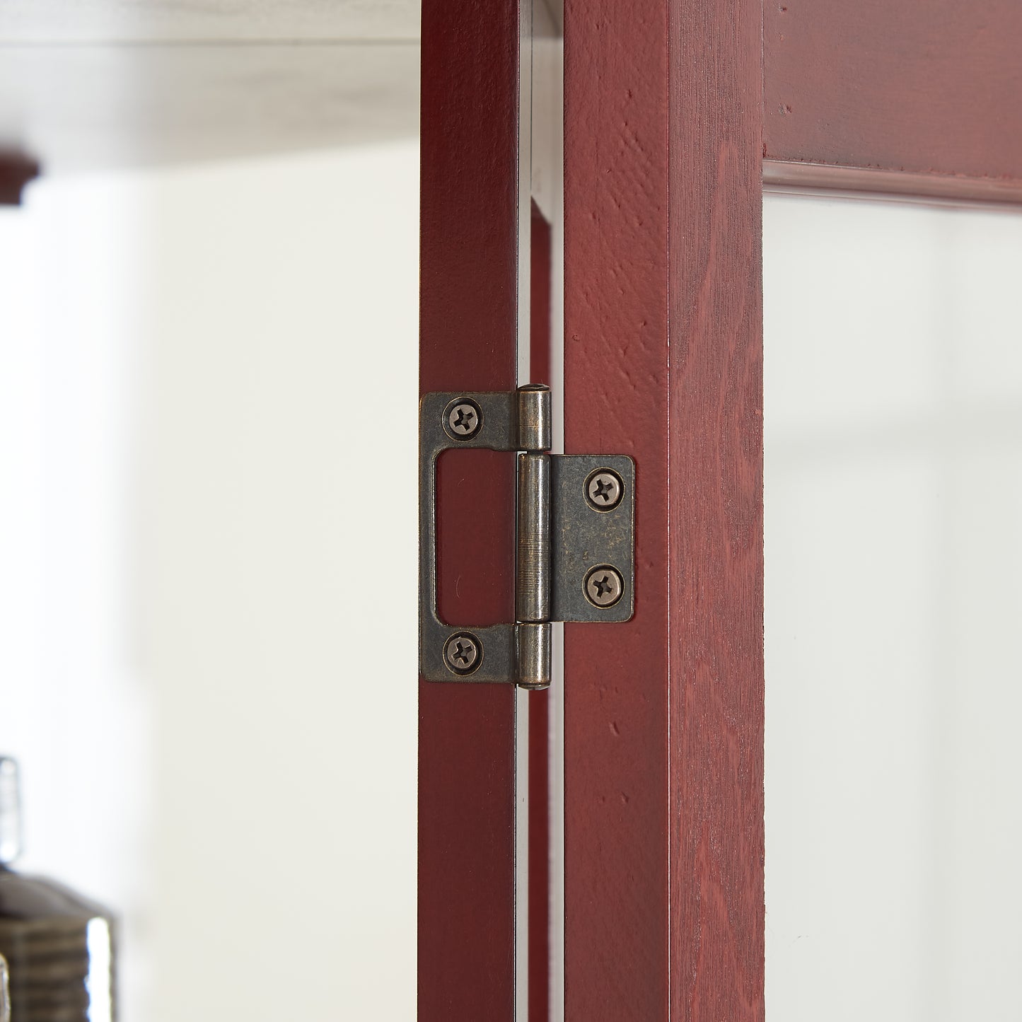 Detail of antique brass door hinge on a dark cherry wood cabinet