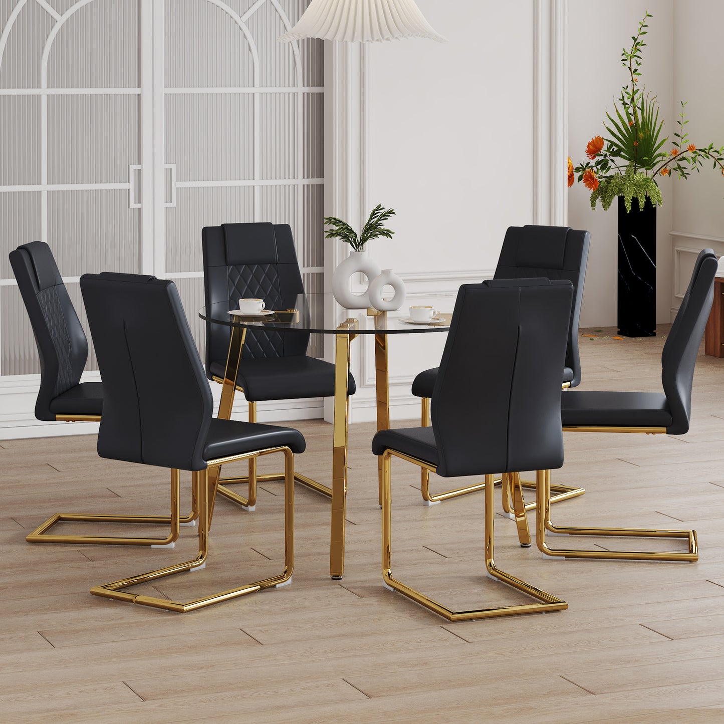 Black faux leather dining chairs with gold metal legs around a glass table