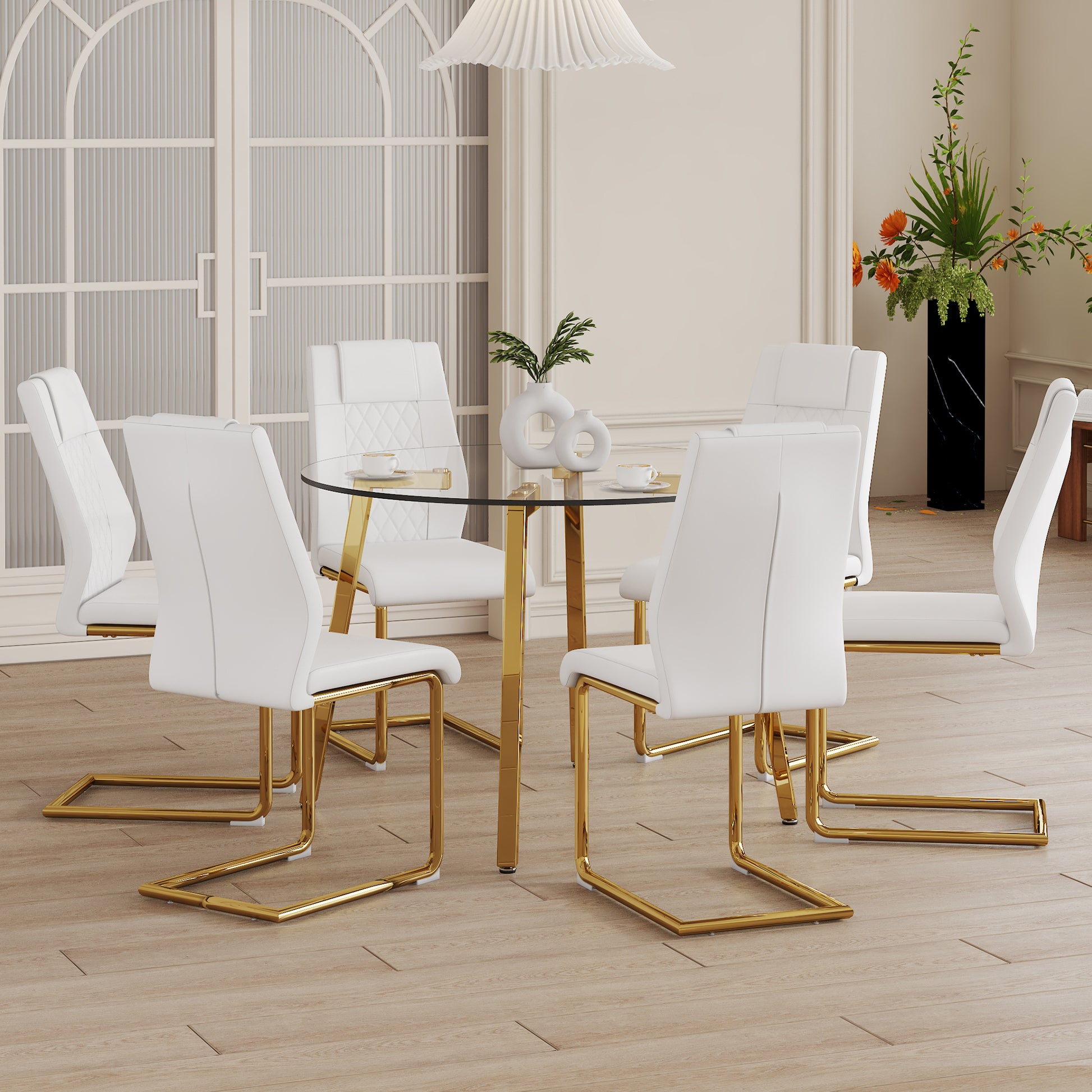 White leather dining chairs with gold legs surrounding a glass table