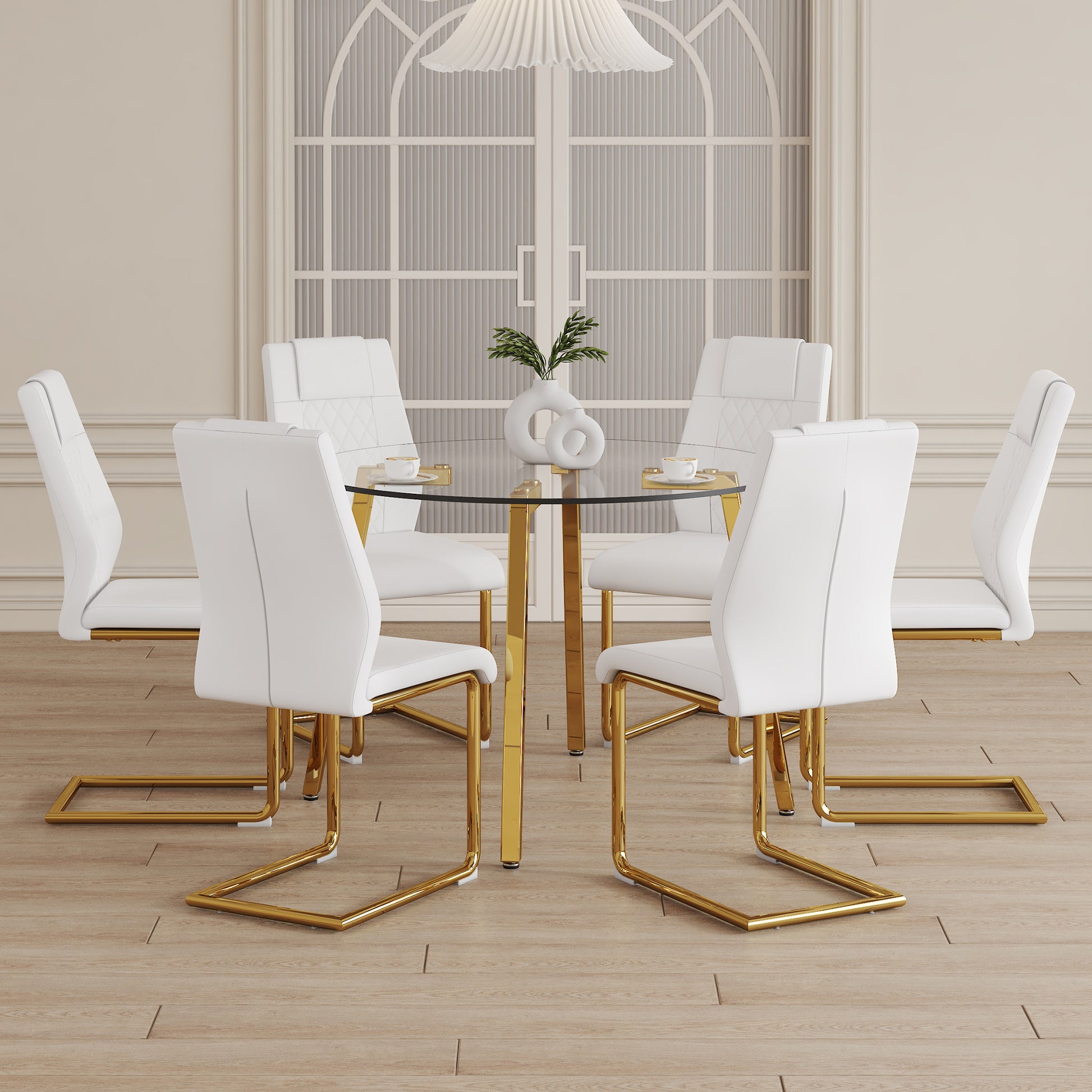 White faux leather dining chairs with gold sled legs around a glass table