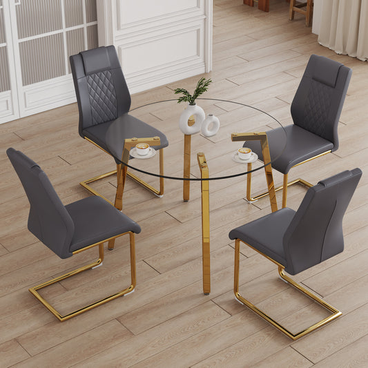 Round glass dining table with four gray upholstered chairs and gold legs