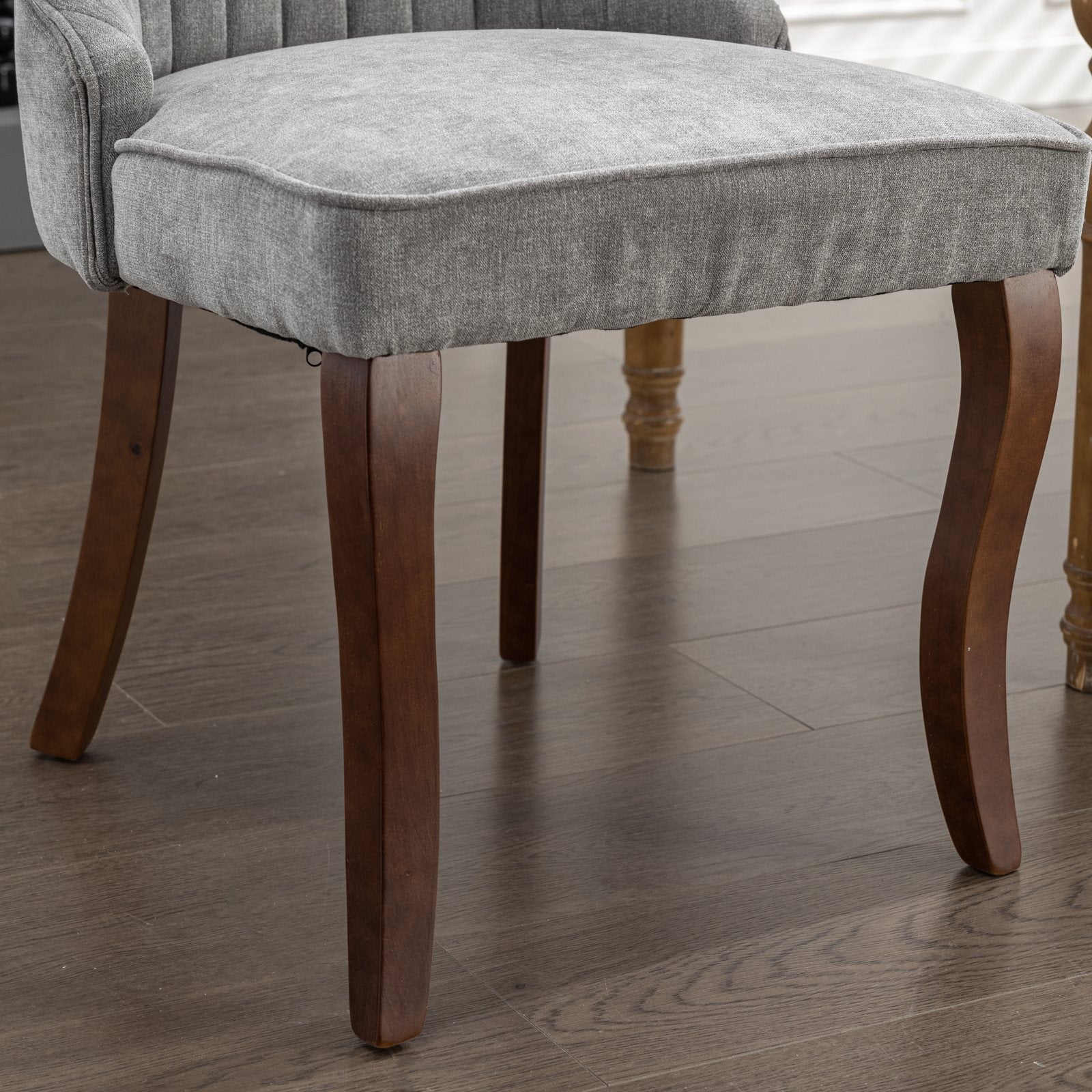 Closeup of plush grey upholstered dining chair with dark wood legs