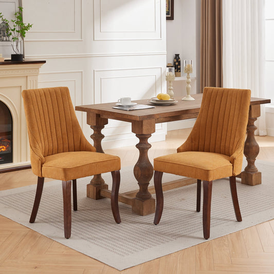 Two textured mustard yellow dining chairs with channel tufting and dark wooden legs arranged around a rustic farmhouse table