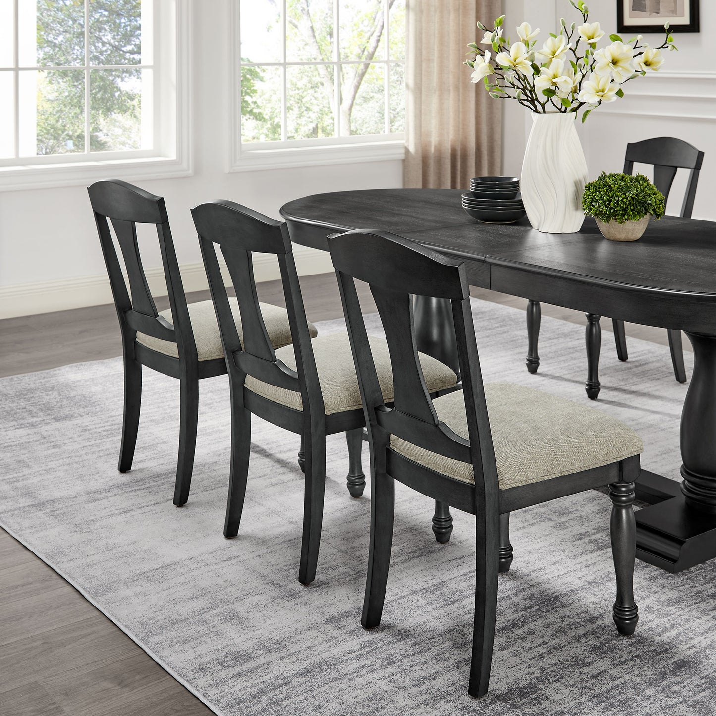 Dark gray dining chairs with upholstered seats arranged around an oval table