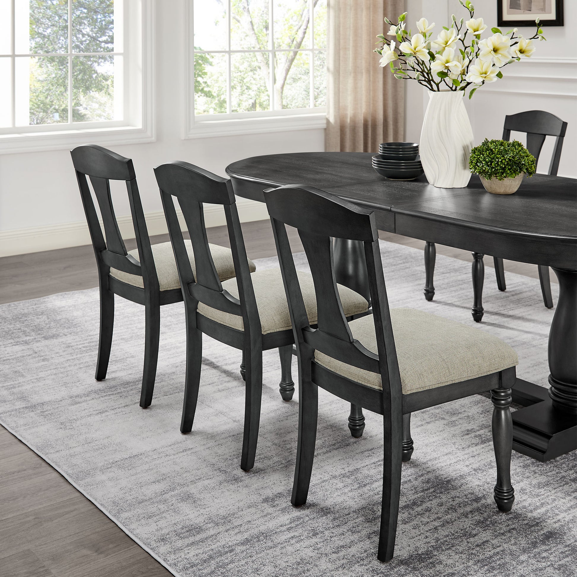 Dark gray dining chairs with upholstered seats arranged around an oval table