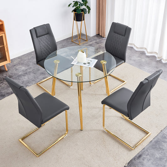 Round glass dining table with four dark gray upholstered chairs and gold metal legs