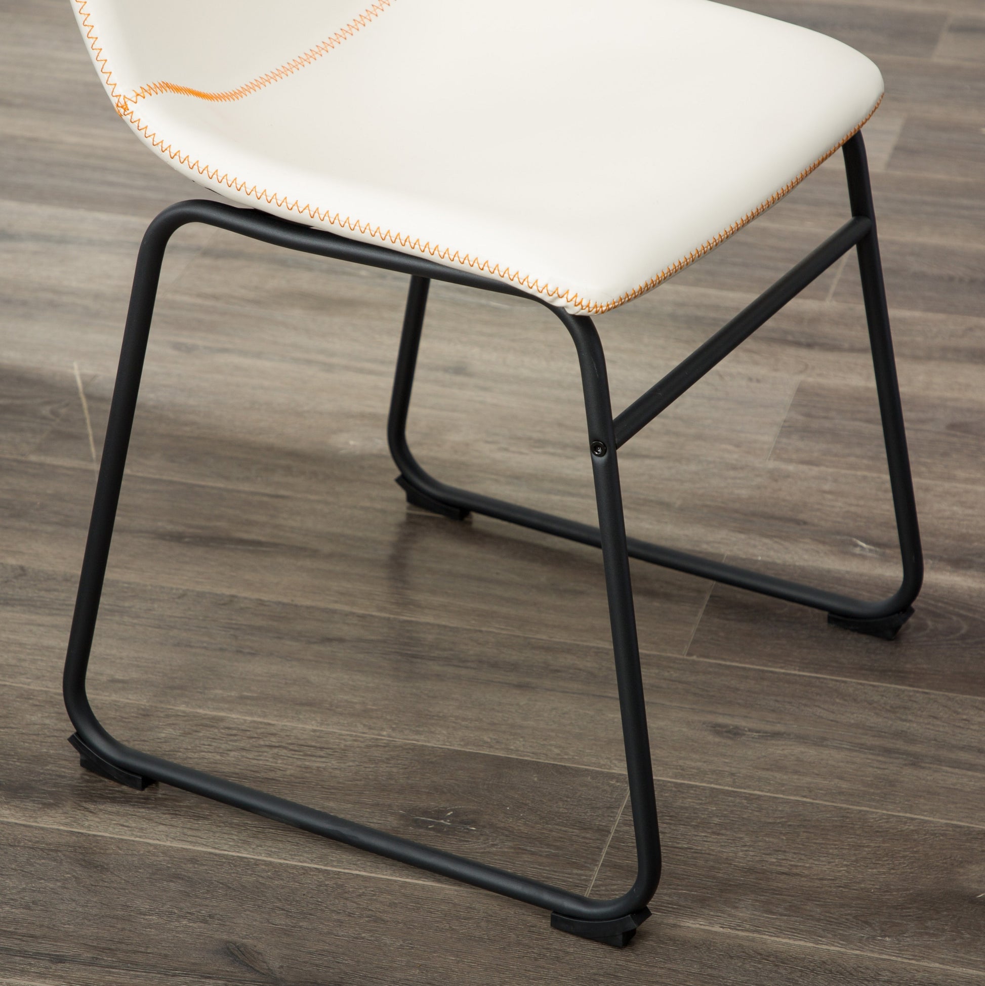 White faux leather dining chair with orange contrast stitching and black metal legs