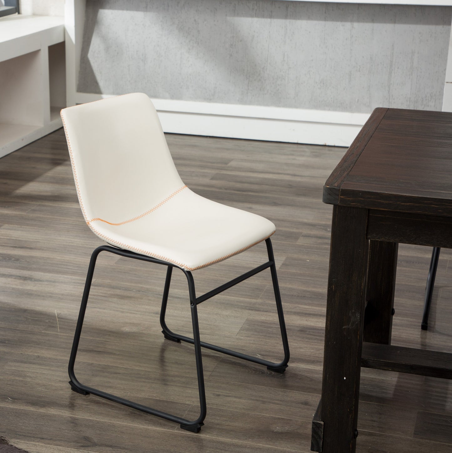 Cream upholstered dining chair with orange stitching and black metal legs
