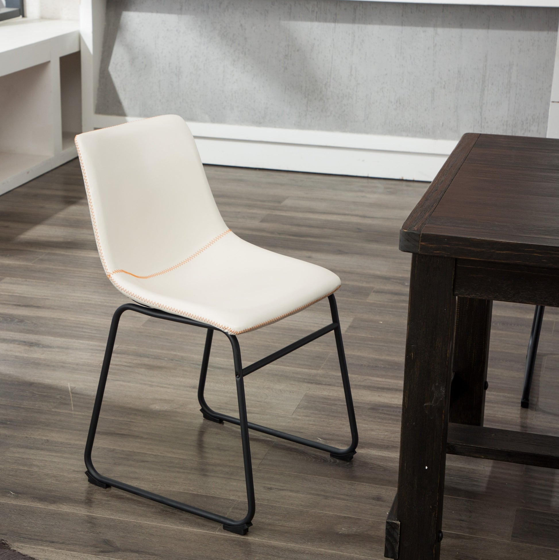 Cream upholstered dining chair with orange stitching and black metal legs