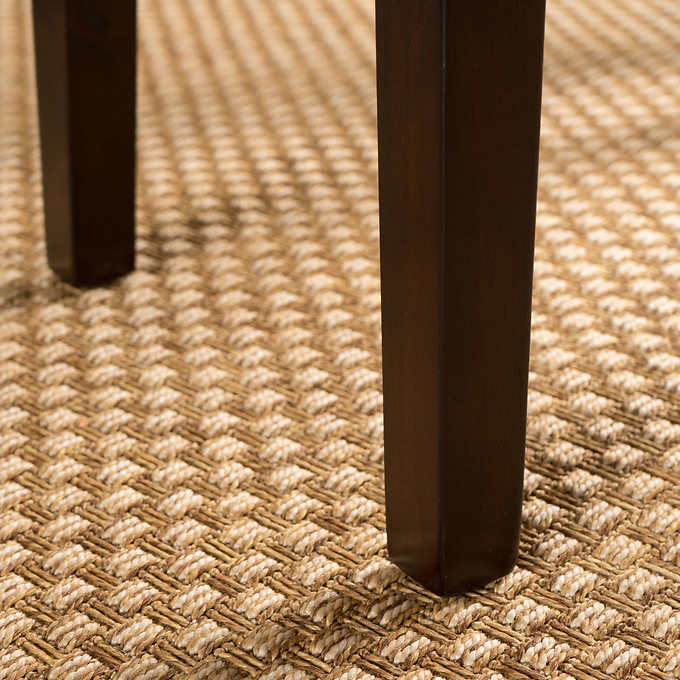 Dark wood furniture legs on a textured beige woven rug