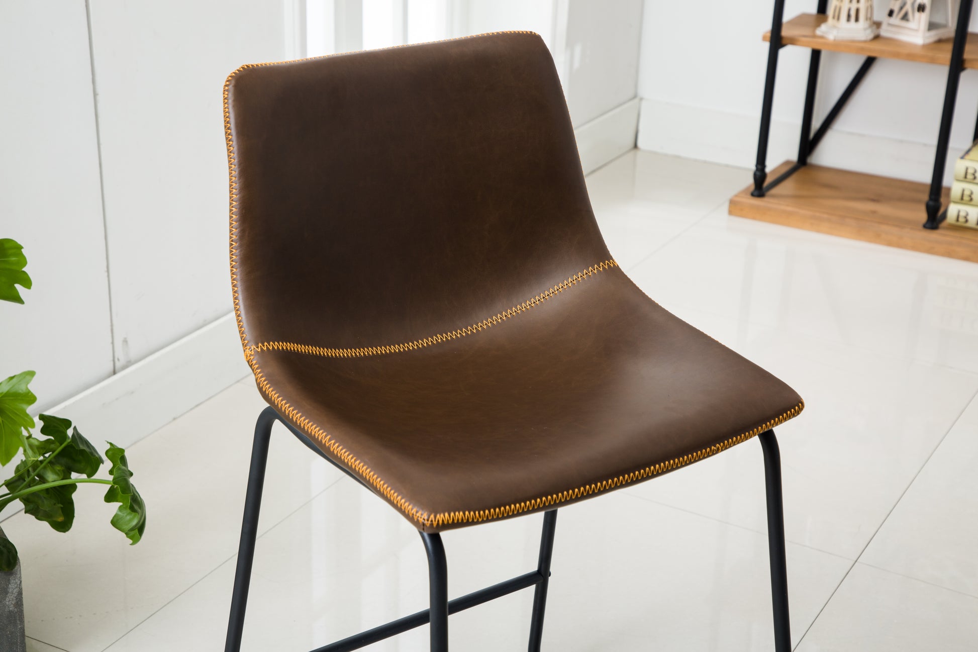Brown faux leather bar stool with orange stitching and black metal legs