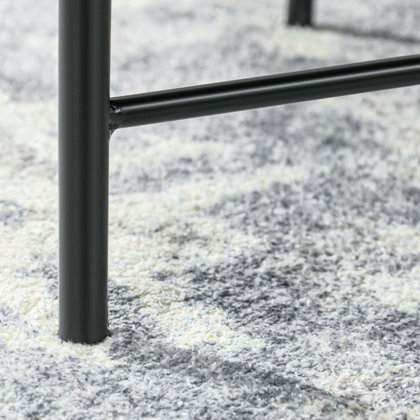 Closeup of matte black metal table leg detail on a textured rug