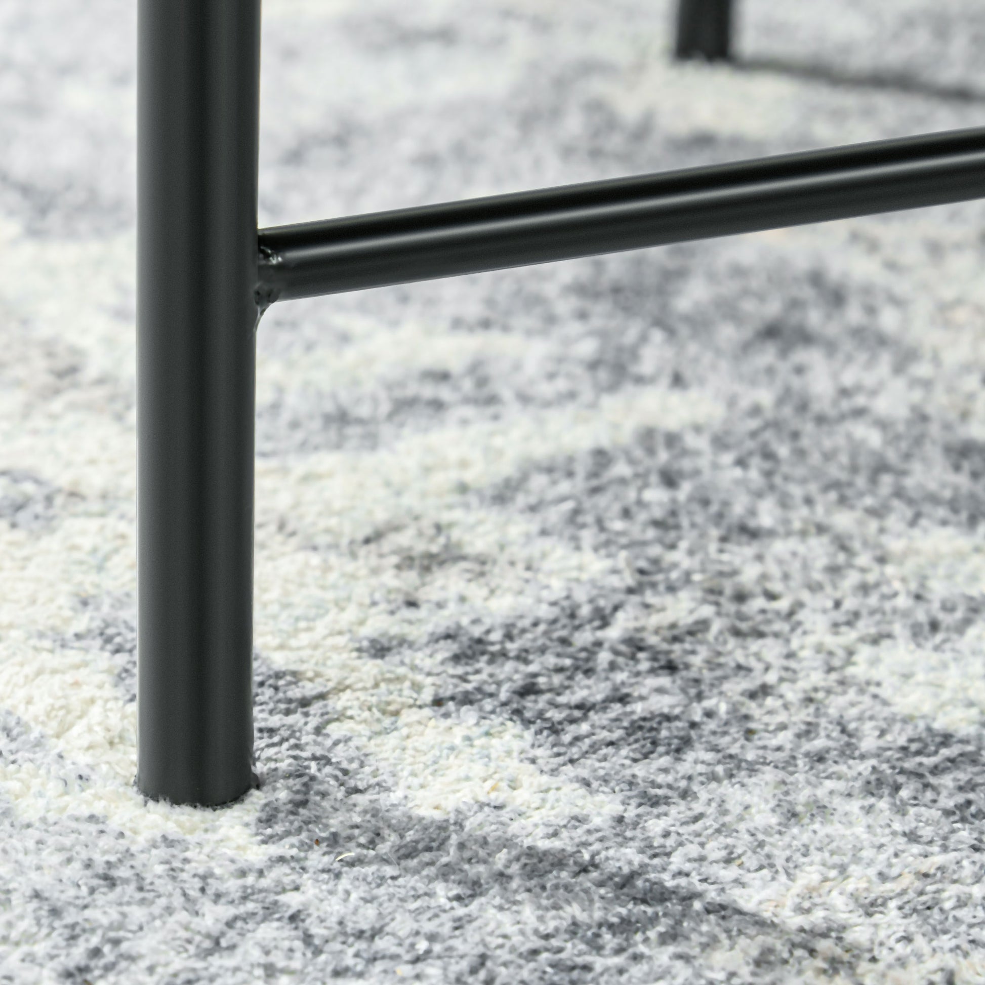 Closeup of matte black metal table leg detail on a textured rug