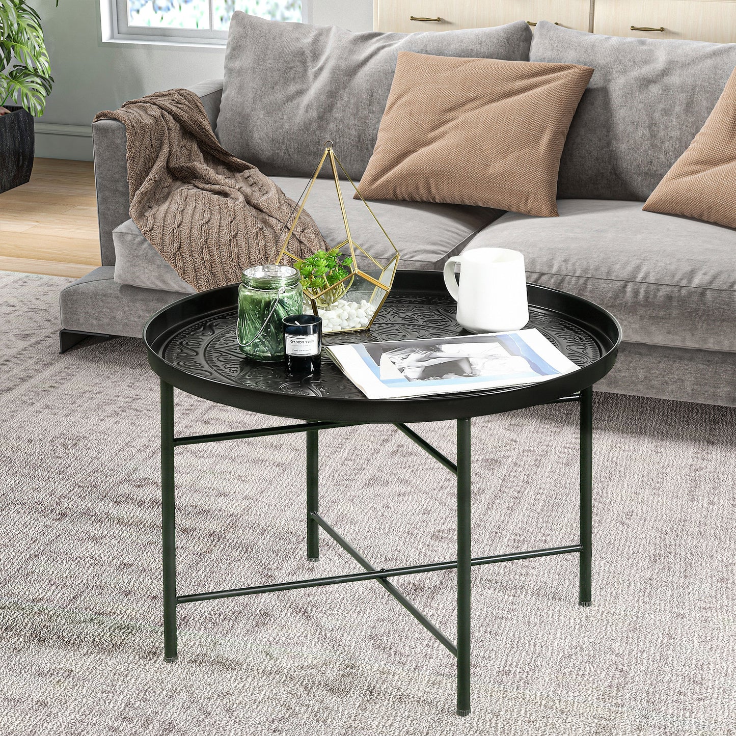 Round black metal tray table with ornate embossed pattern