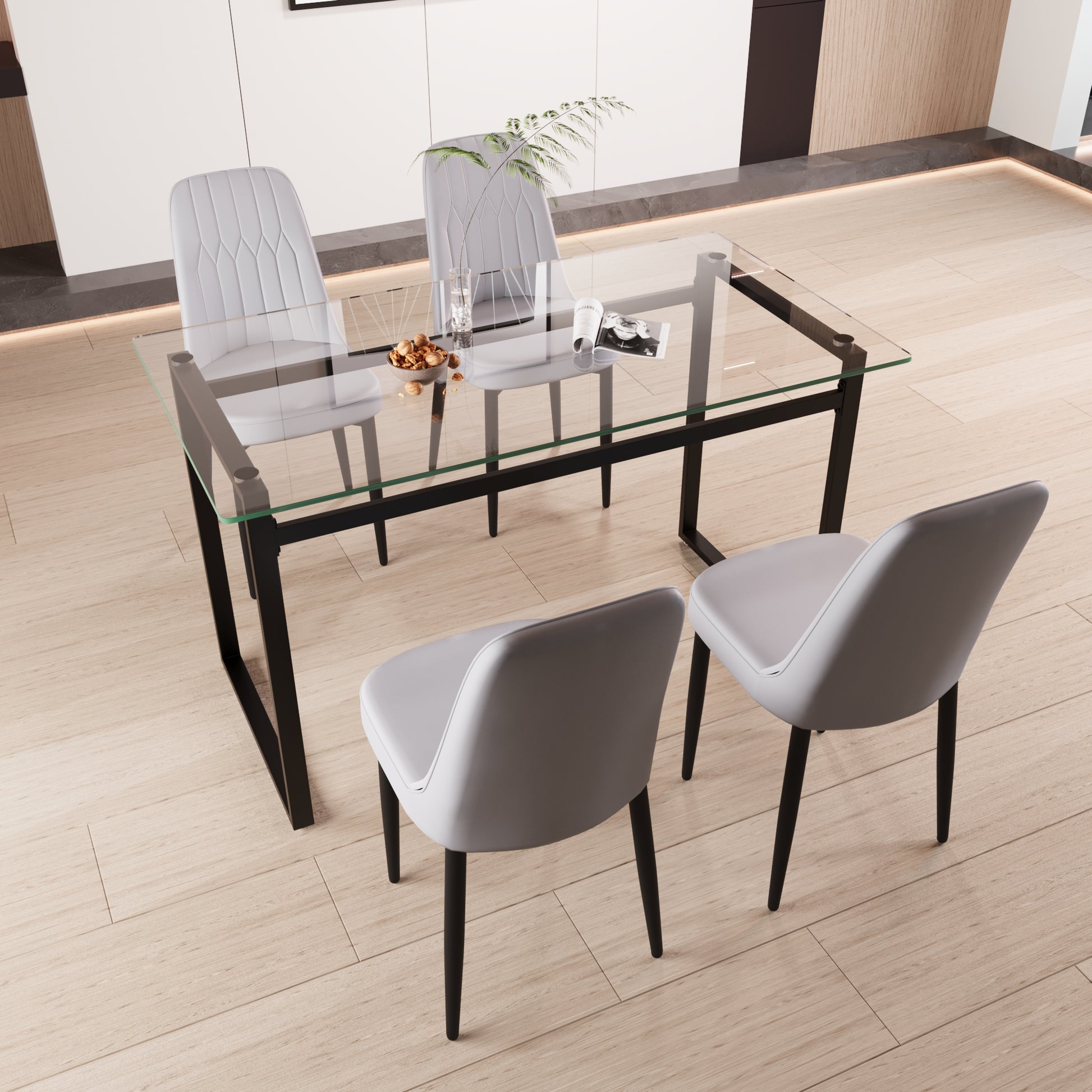 Glass top dining table with black metal frame and four grey upholstered chairs