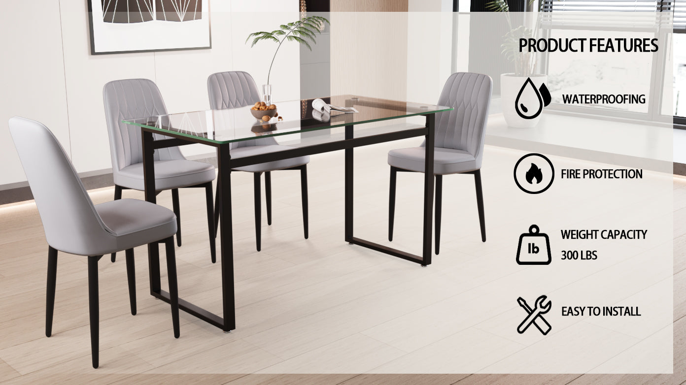 Glass top dining table with four grey upholstered chairs