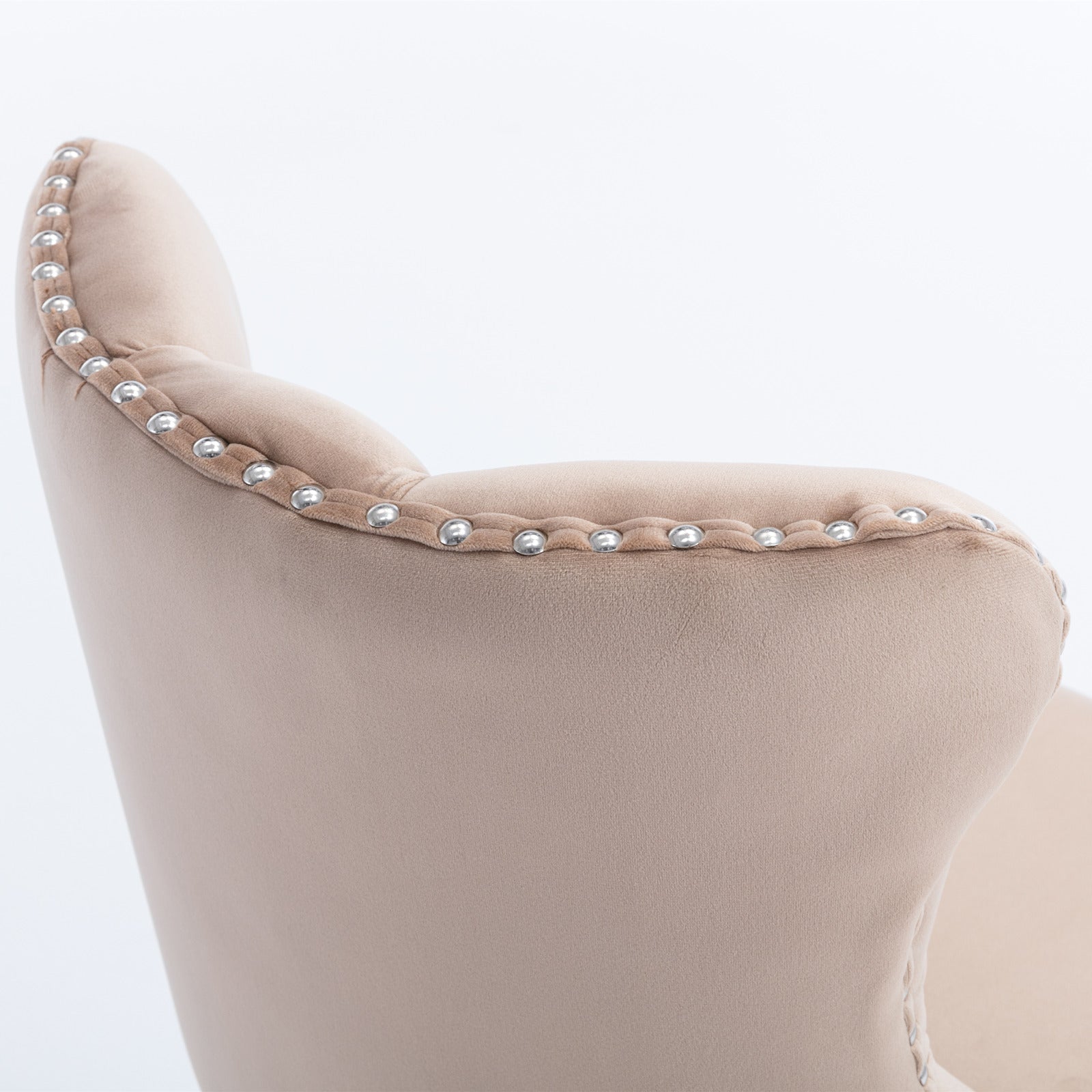 Beige velvet armchair detail with silver nailhead trim accents and button tufting