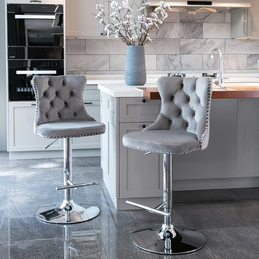 Two grey tufted velvet bar stools with chrome accents and adjustable height perfect for a modern kitchen island
