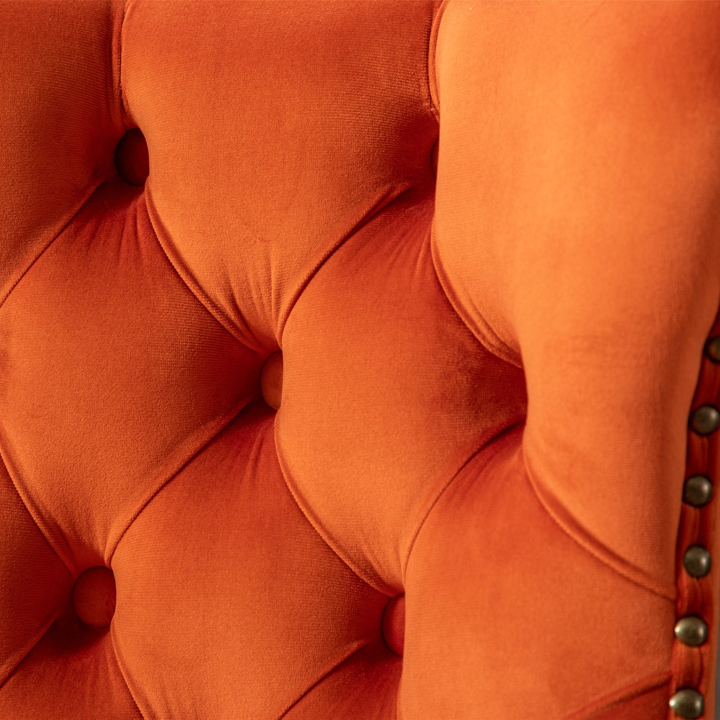 Orange velvet tufted accent chair detail with brass nailhead trim