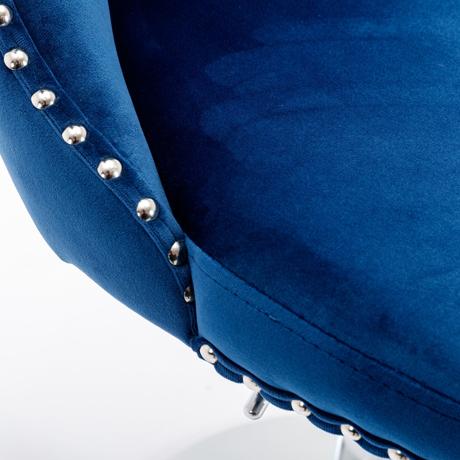 Closeup of rich royal blue velvet armchair armrest with silver nailhead trim