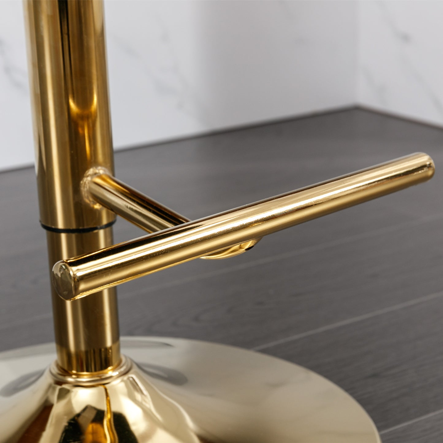 Polished gold metal footrest on a modern bar stool base