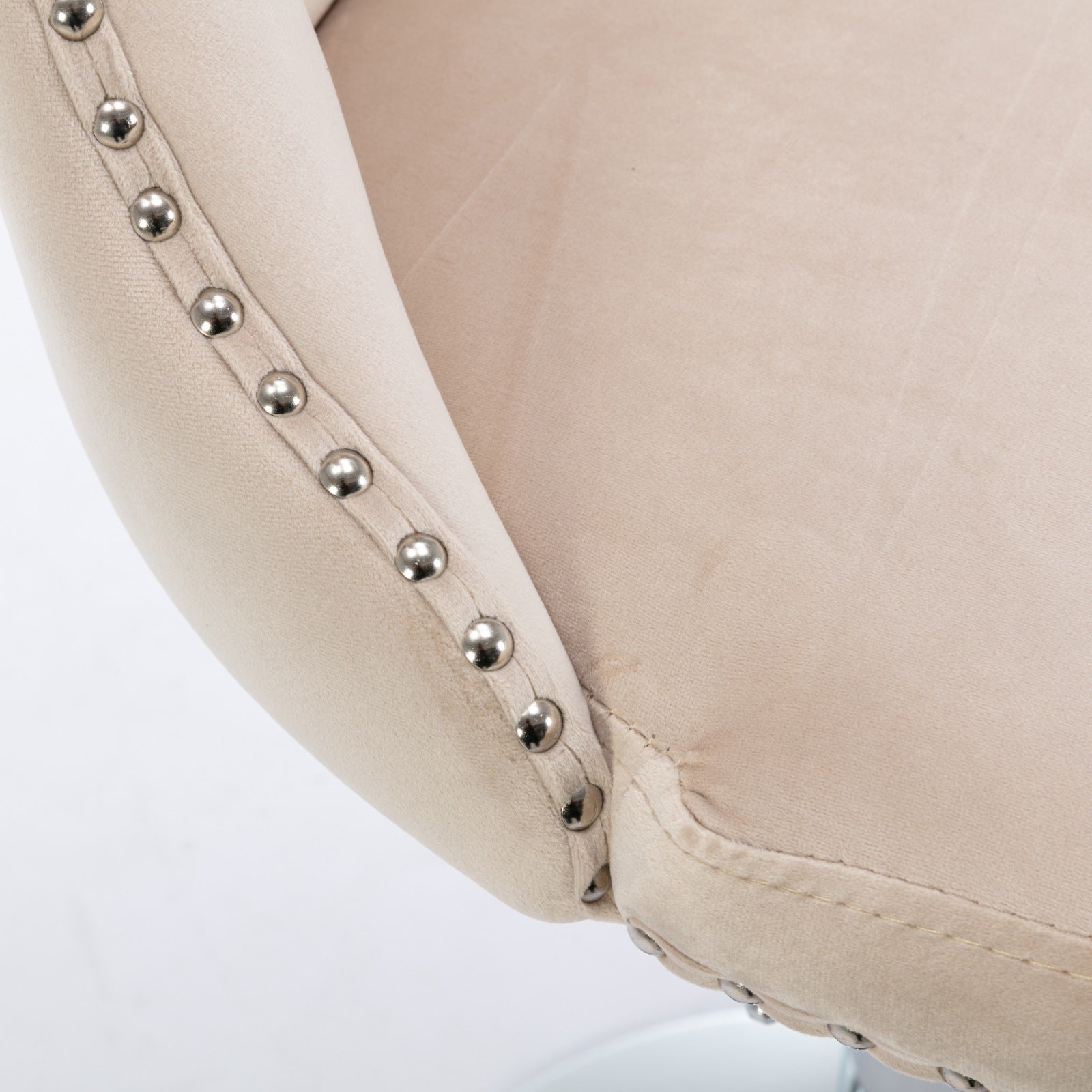 Closeup of a beige velvet bar stool armrest with silver nailhead trim