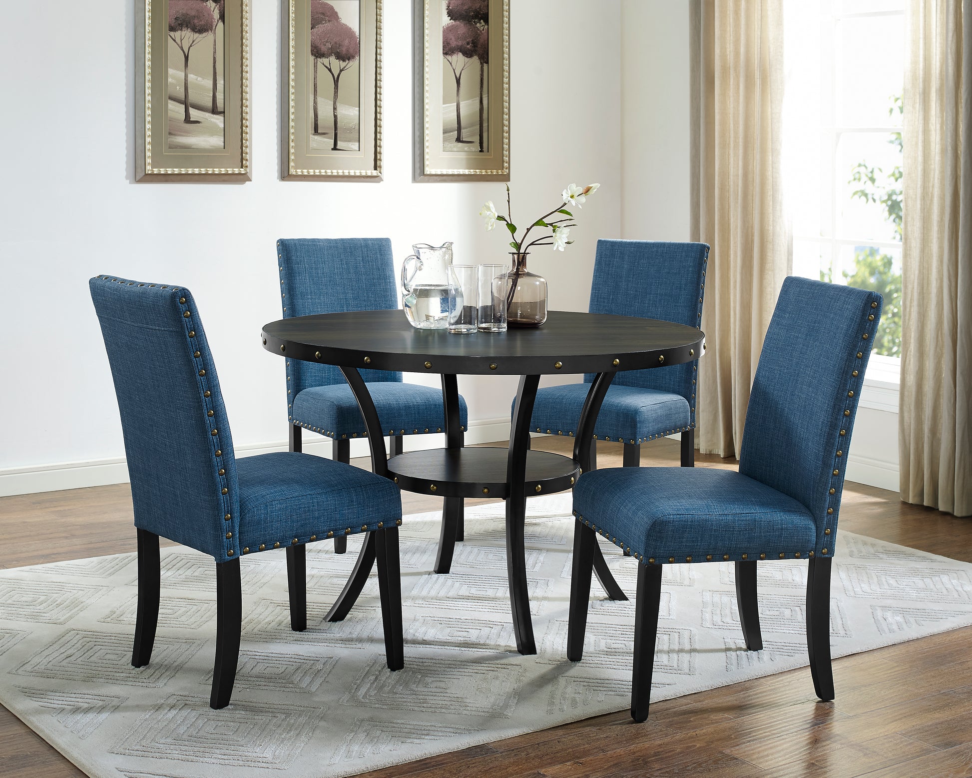Round dark wood dining table with blue upholstered chairs and brass studs