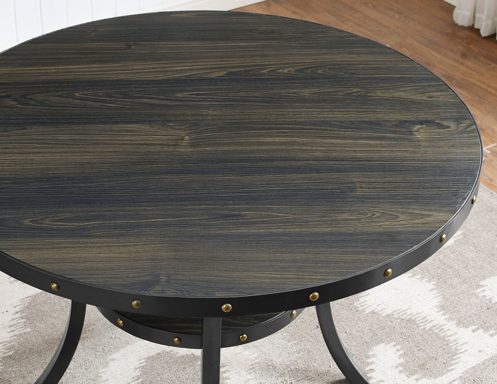 Round distressed wood coffee table with black metal frame and brass studs