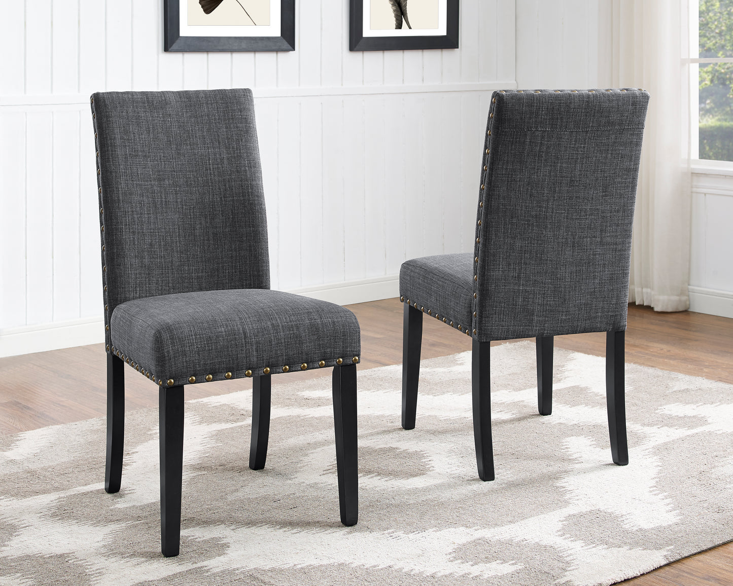 Dark gray upholstered dining chair with brass nailhead trim and black wooden legs