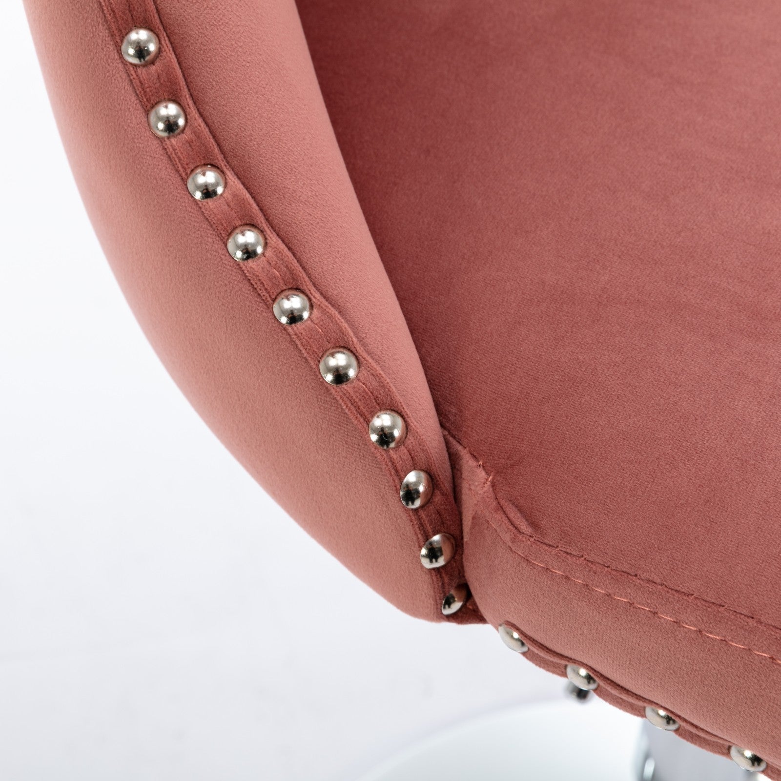 Closeup of rose velvet bar stool with silver nailhead trim detail