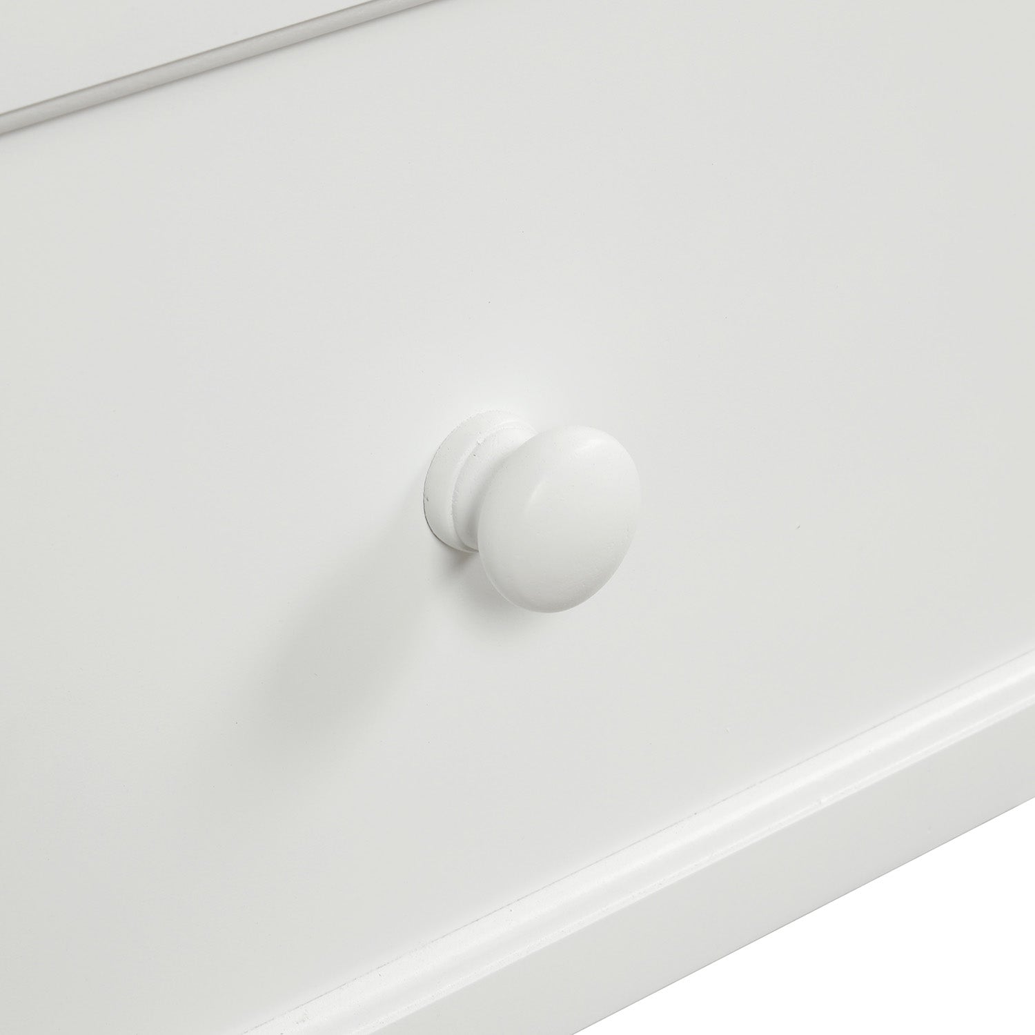Closeup of a smooth white wooden drawer knob on a white dresser front