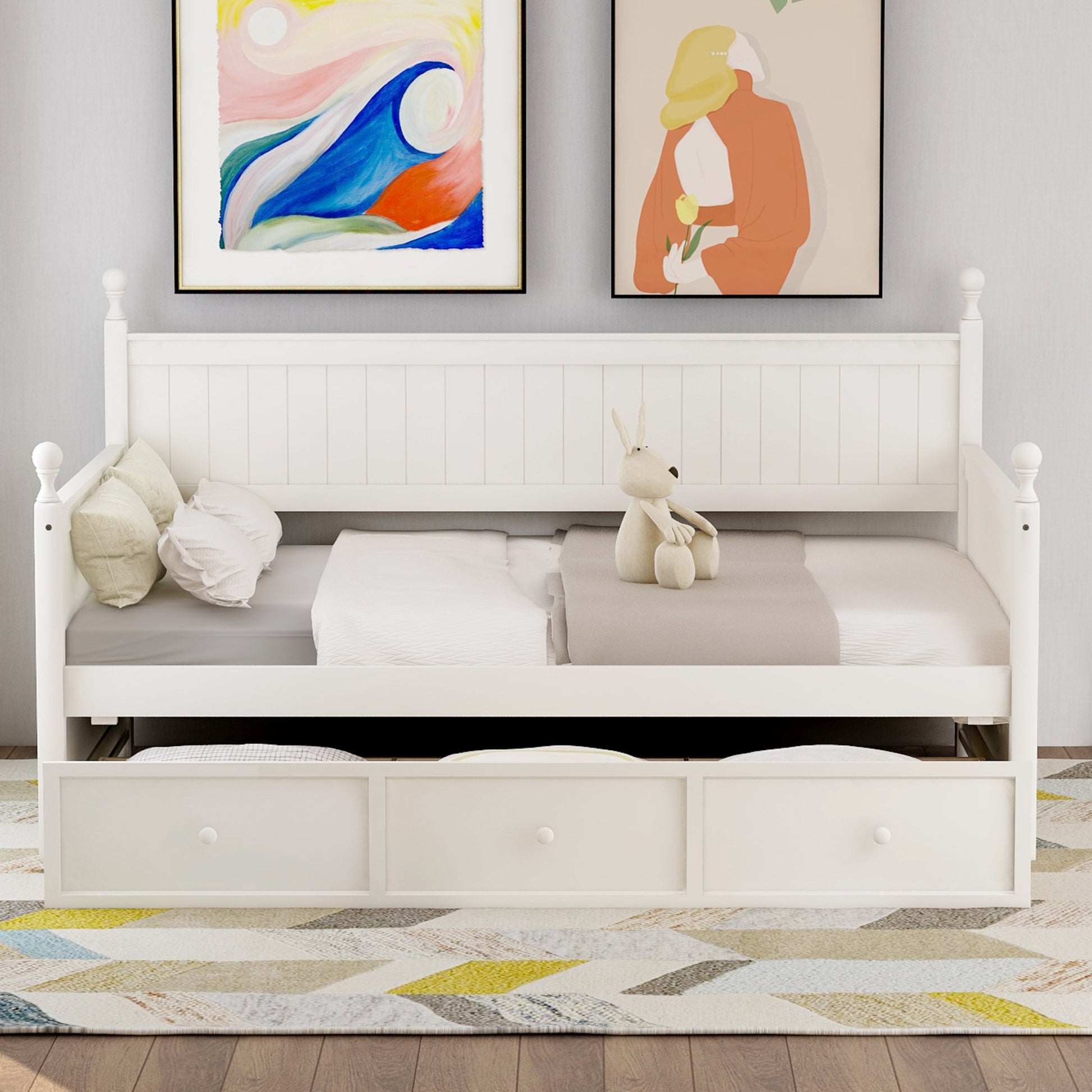 White wooden daybed with three pullout drawers and plush bedding