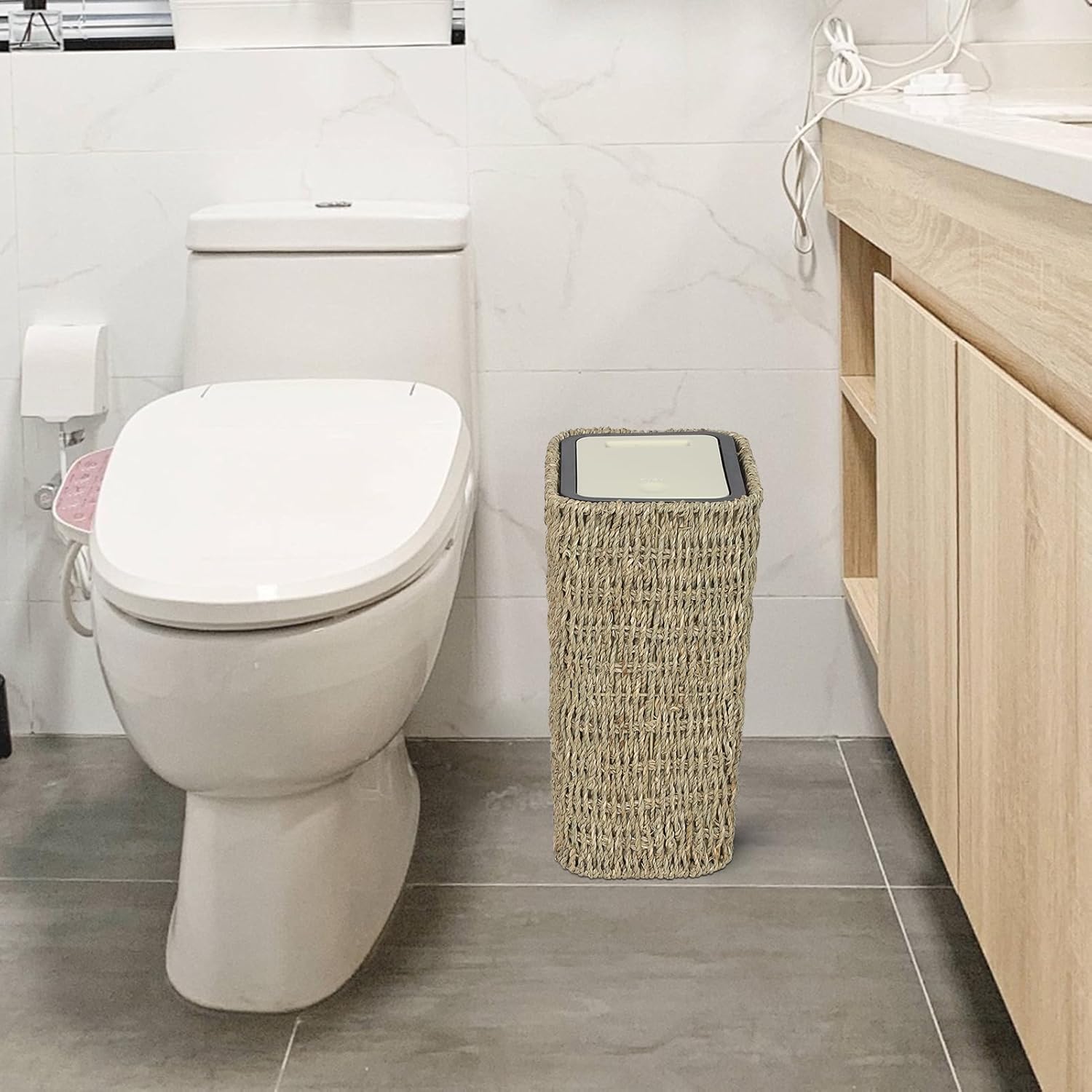 Woven seagrass trash can with lid in bathroom