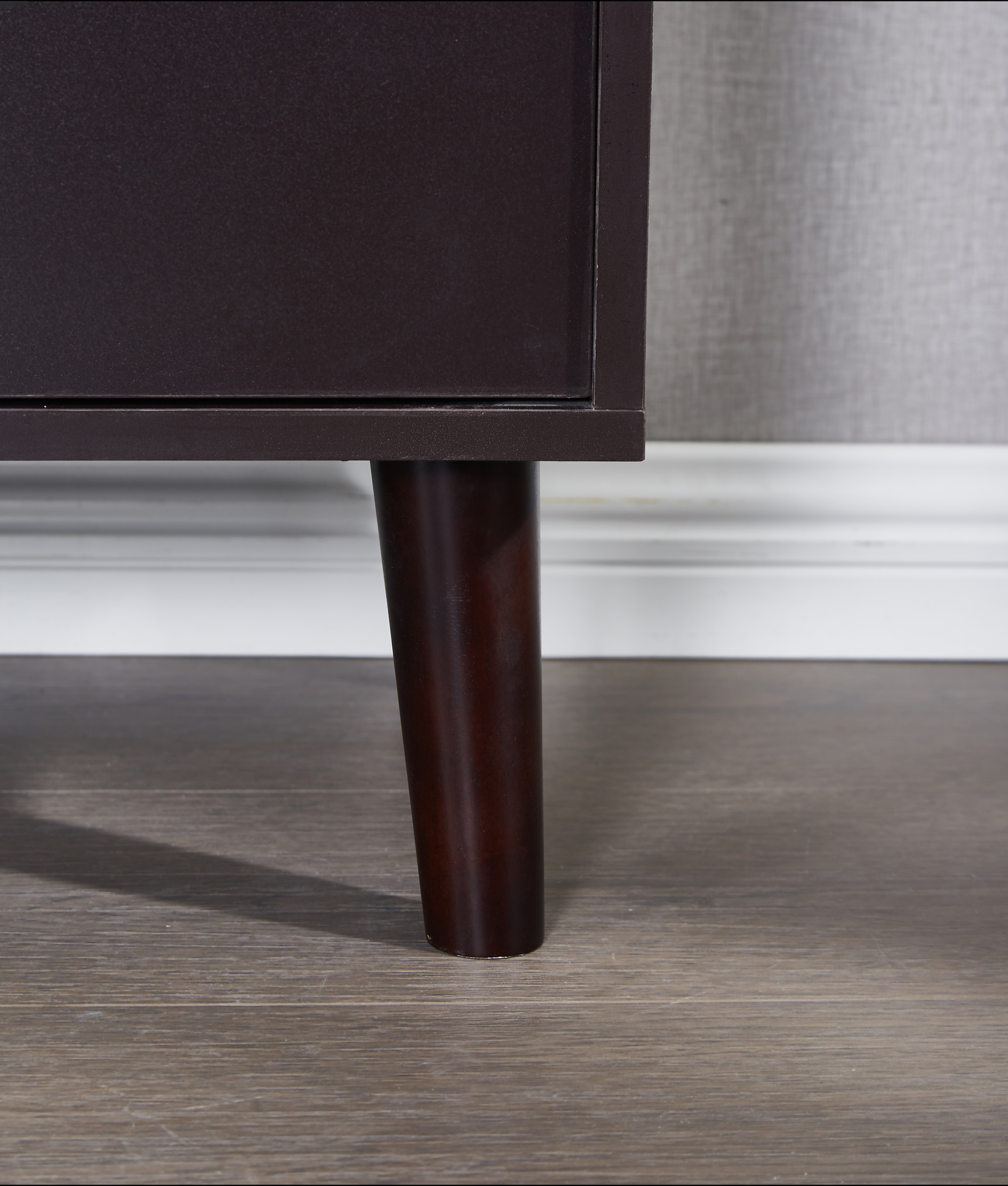 Dark brown tapered dresser leg on a wood floor