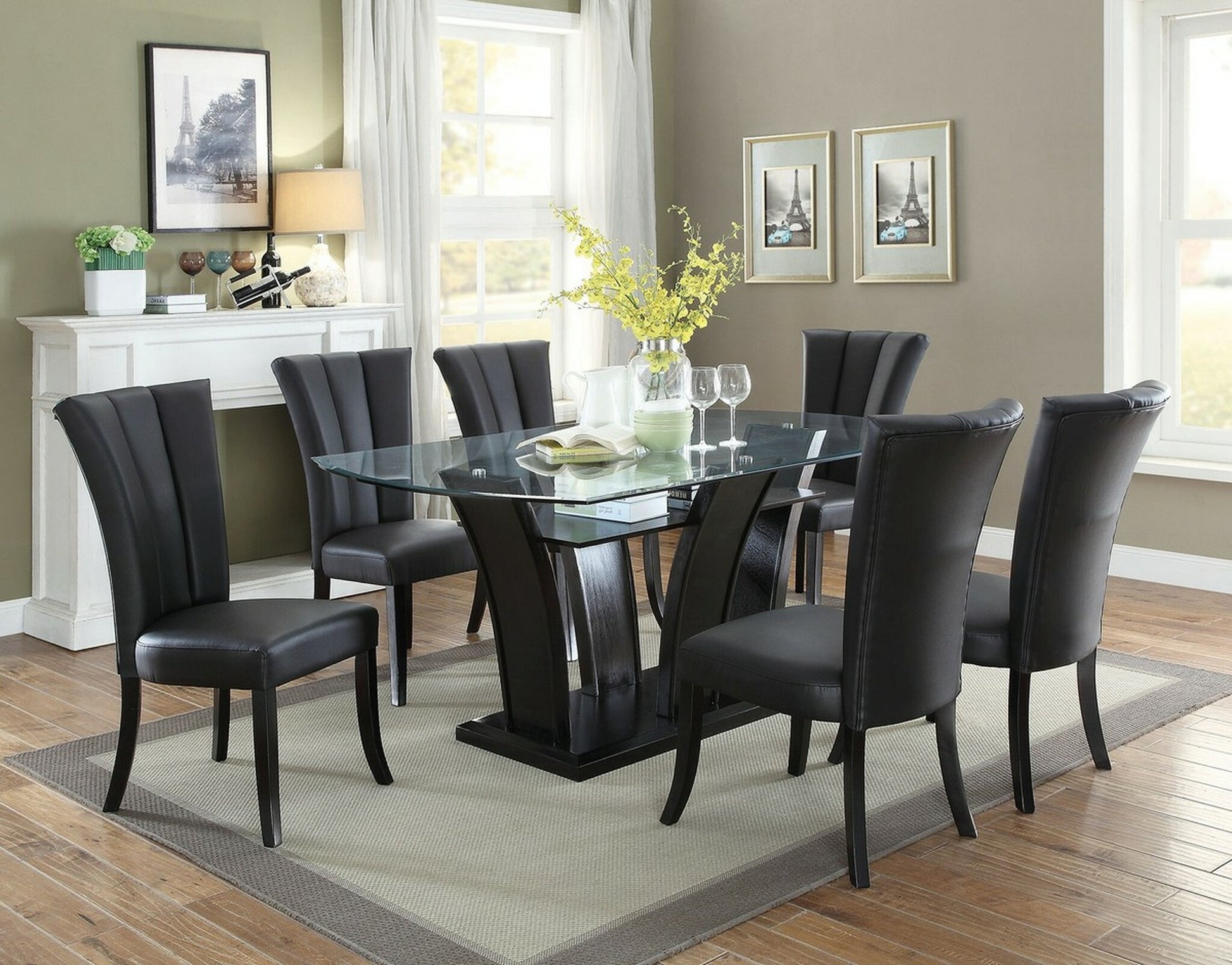 Black leather dining chairs with fluted backs surround a modern glass top dining table