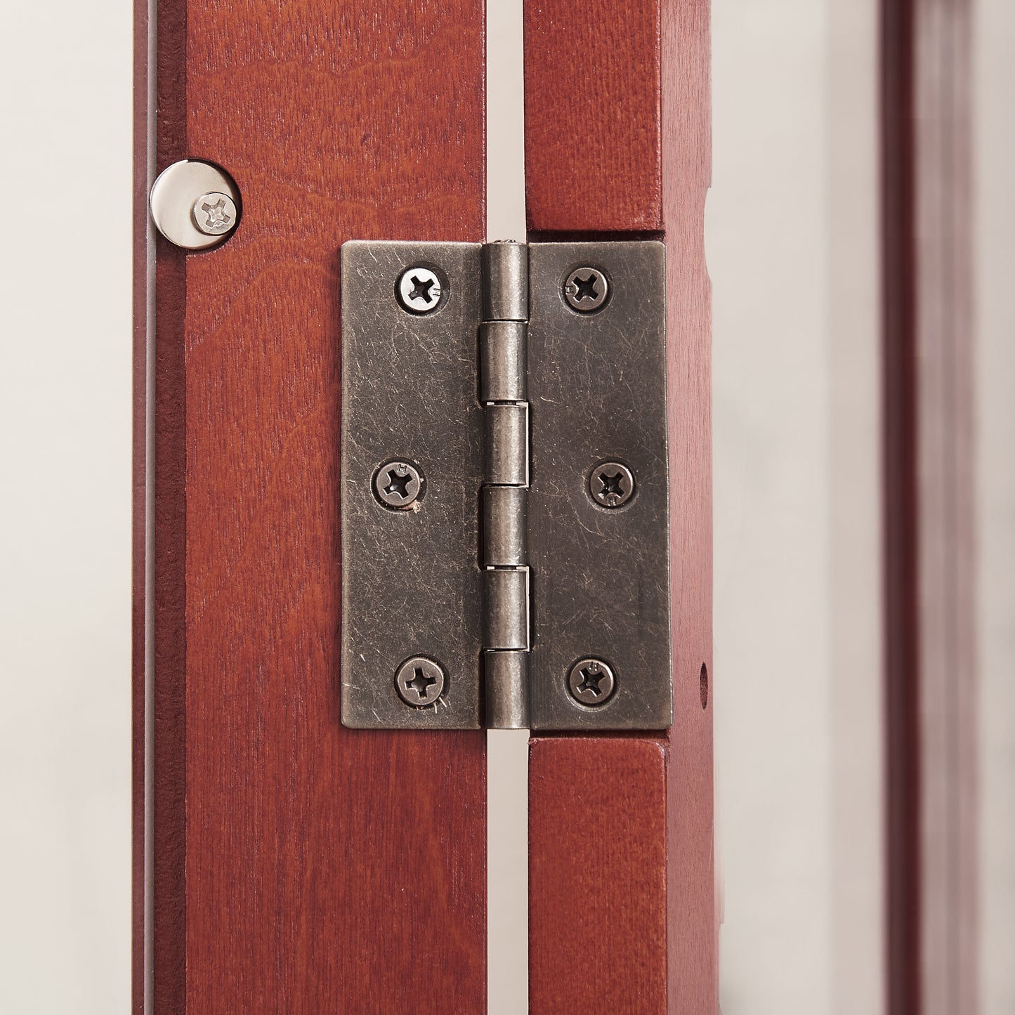 Antique brass cabinet hinge securely attached to dark wood doors