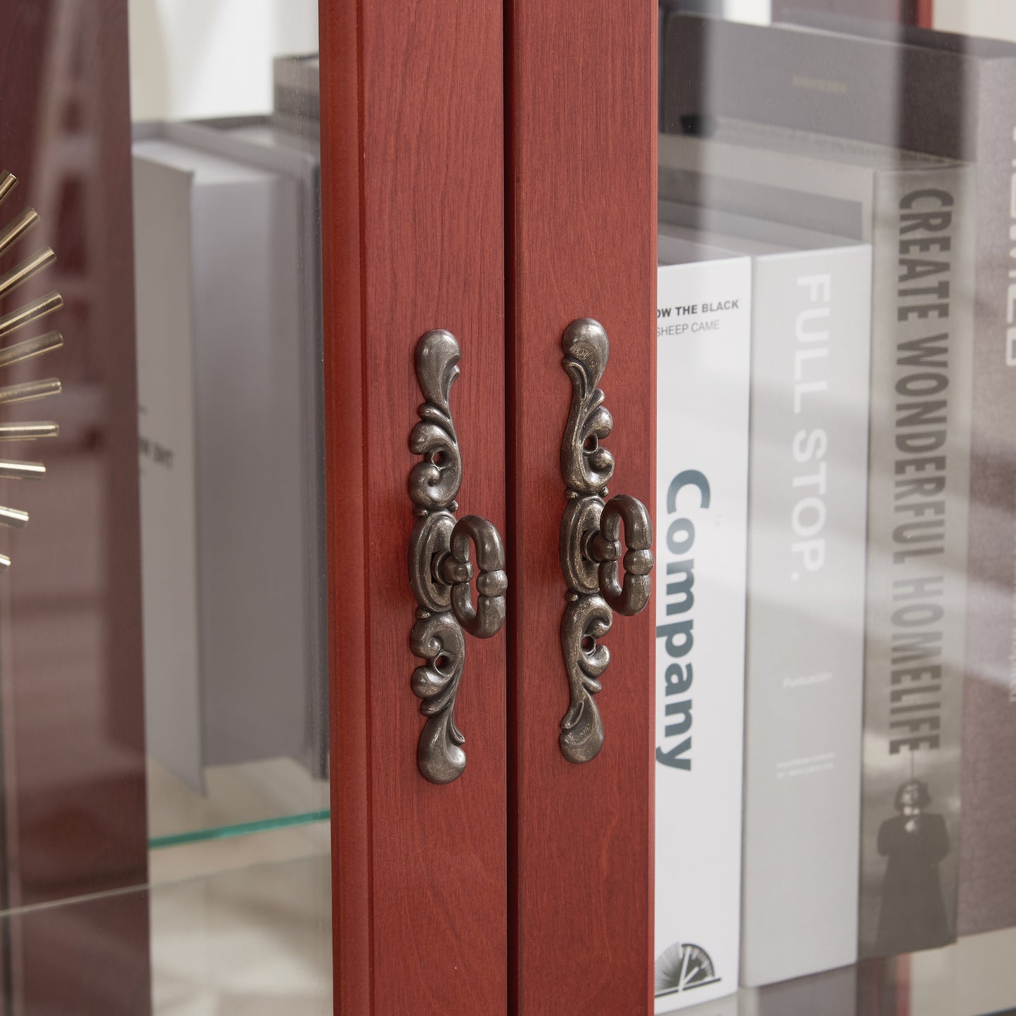 Closeup of antique bronze ornate handles on red wooden display cabinet doors