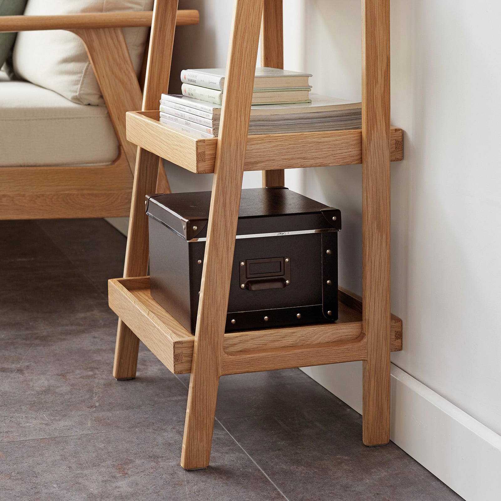 Natural wood ladder shelf with stacked books and storage box