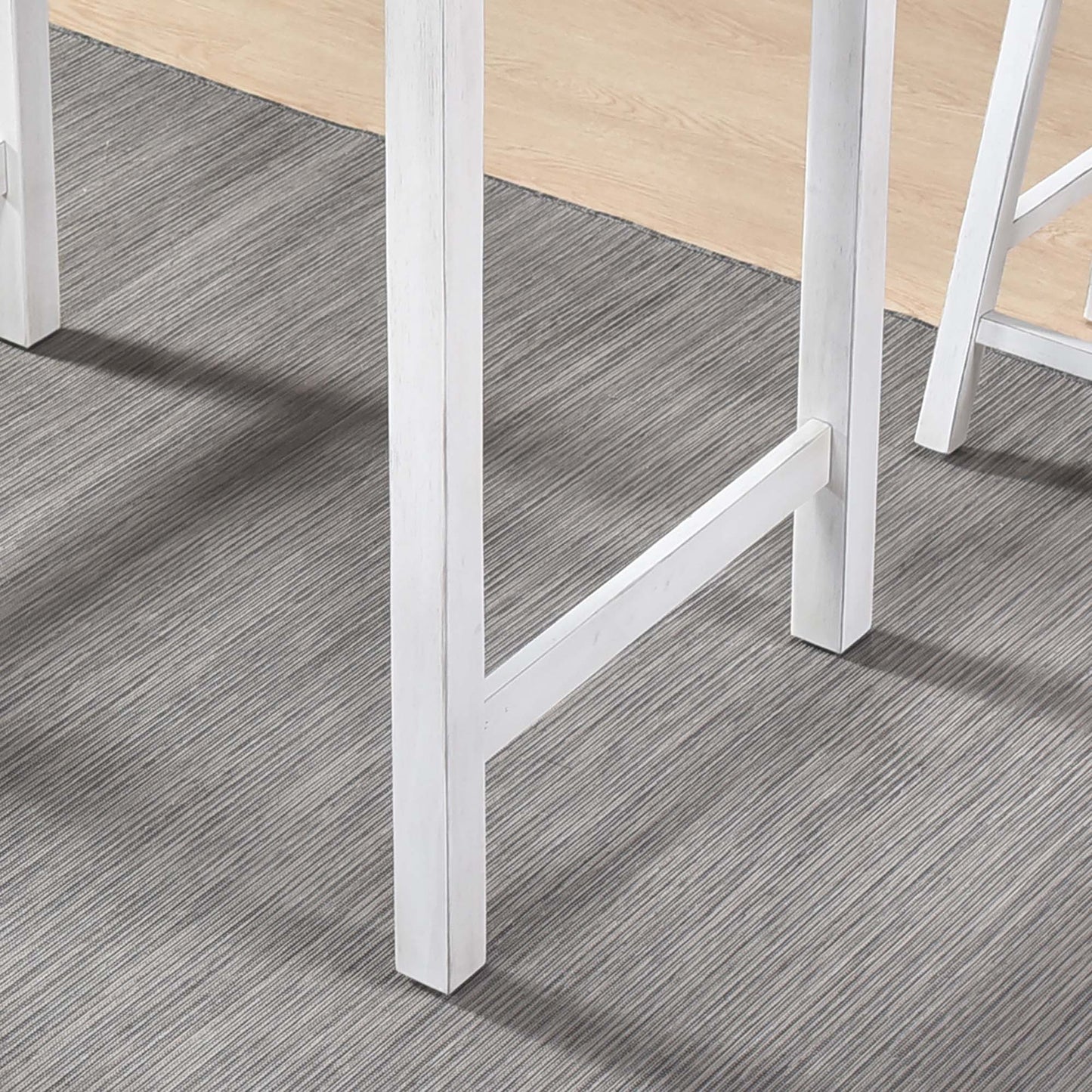 White washed farmhouse dining table legs on grey textured rug
