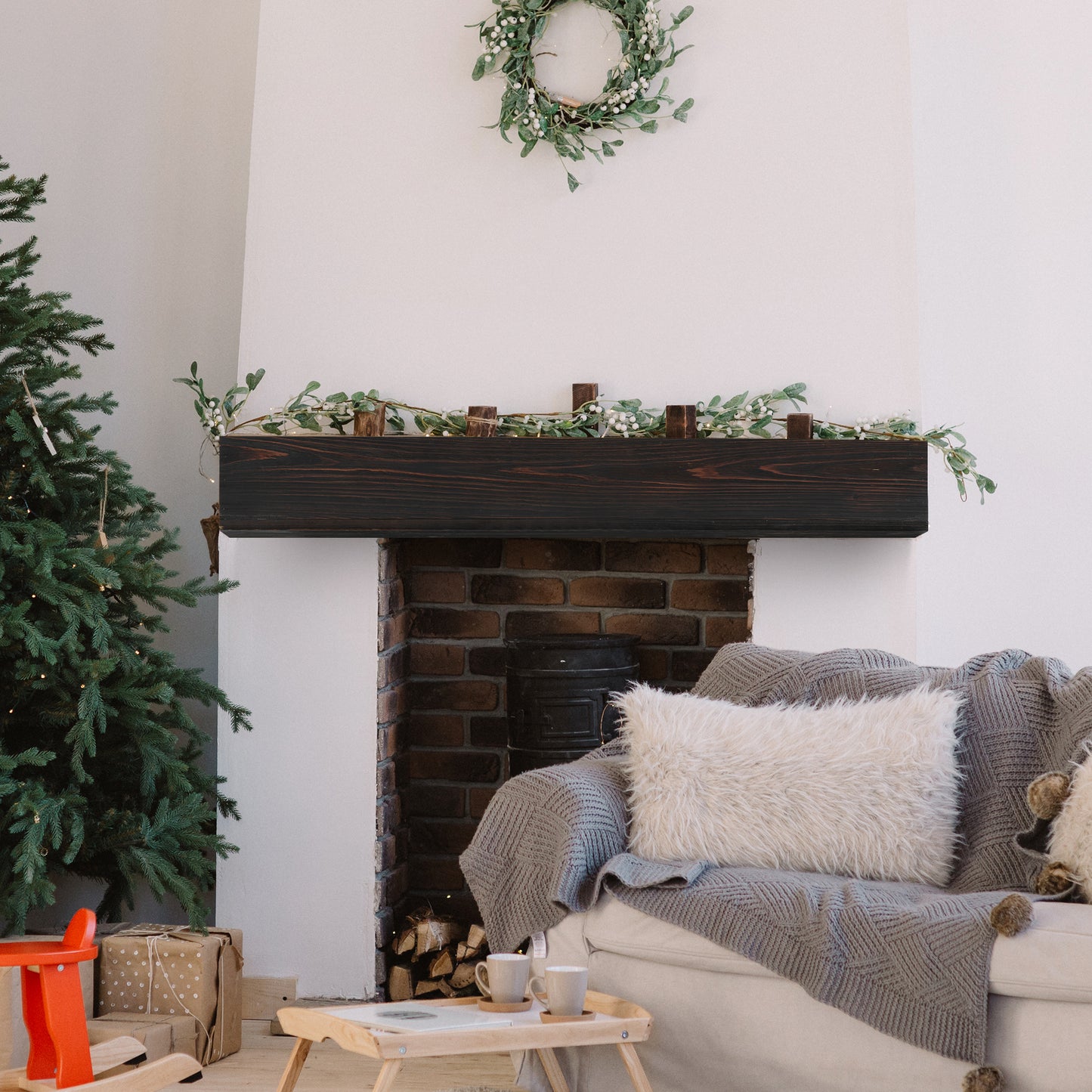 Dark wood fireplace mantel with green garland and white berries