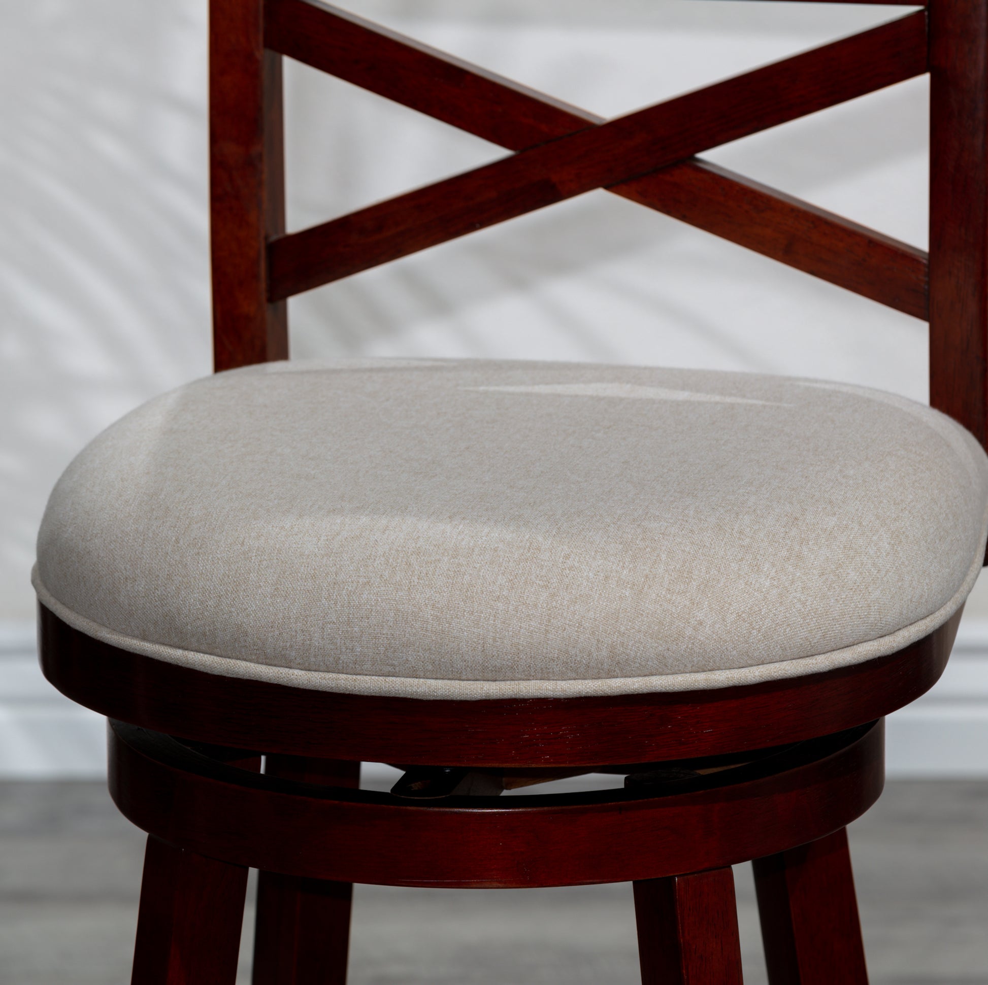 Dark cherry wood bar stool with a beige upholstered seat and xback design