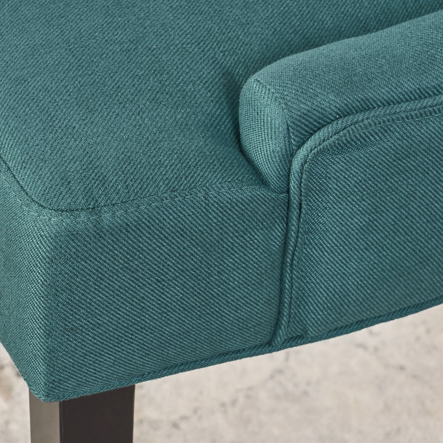 Teal fabric armchair detail with visible stitching and textured weave