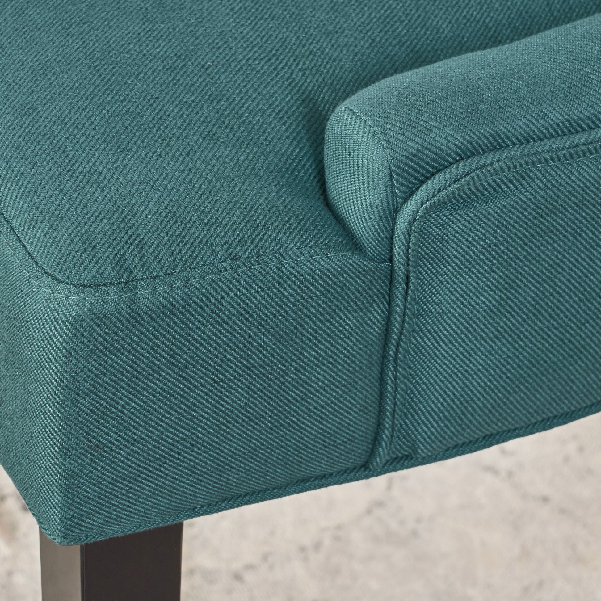 Teal fabric armchair detail with visible stitching and textured weave