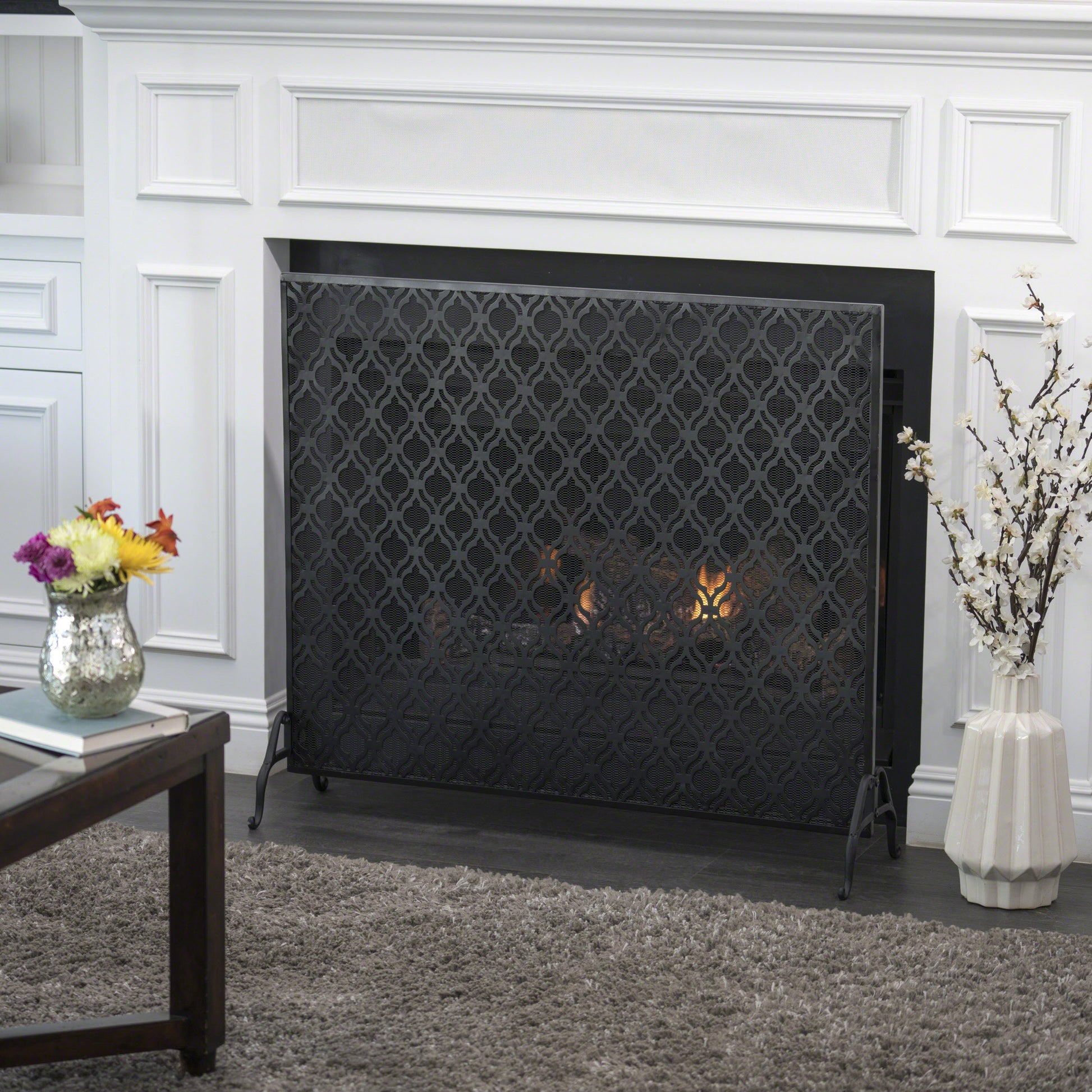 Black metal fireplace screen with ornate quatrefoil pattern