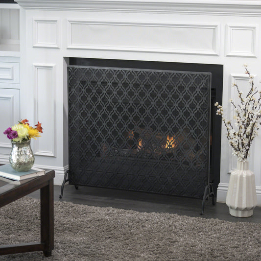 Black metal fireplace screen with ornate quatrefoil pattern
