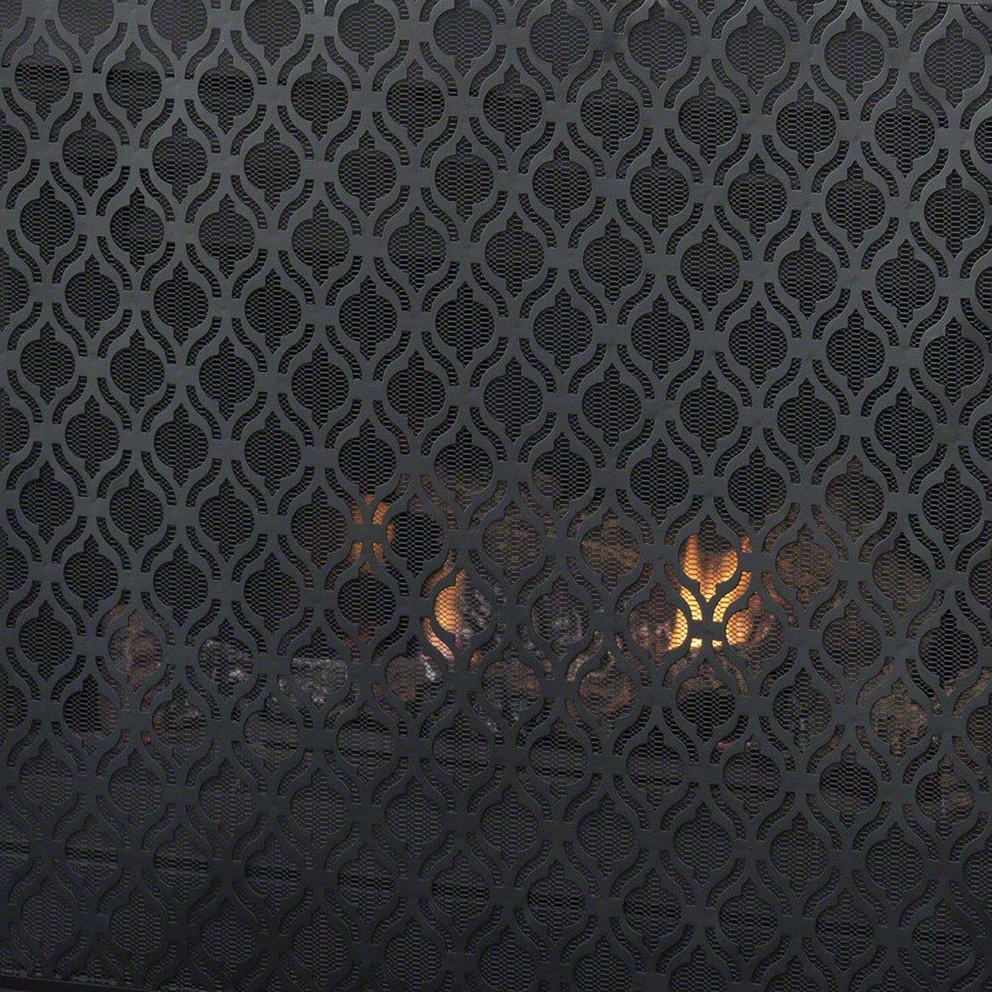 Black metal fireplace screen with ornate quatrefoil pattern