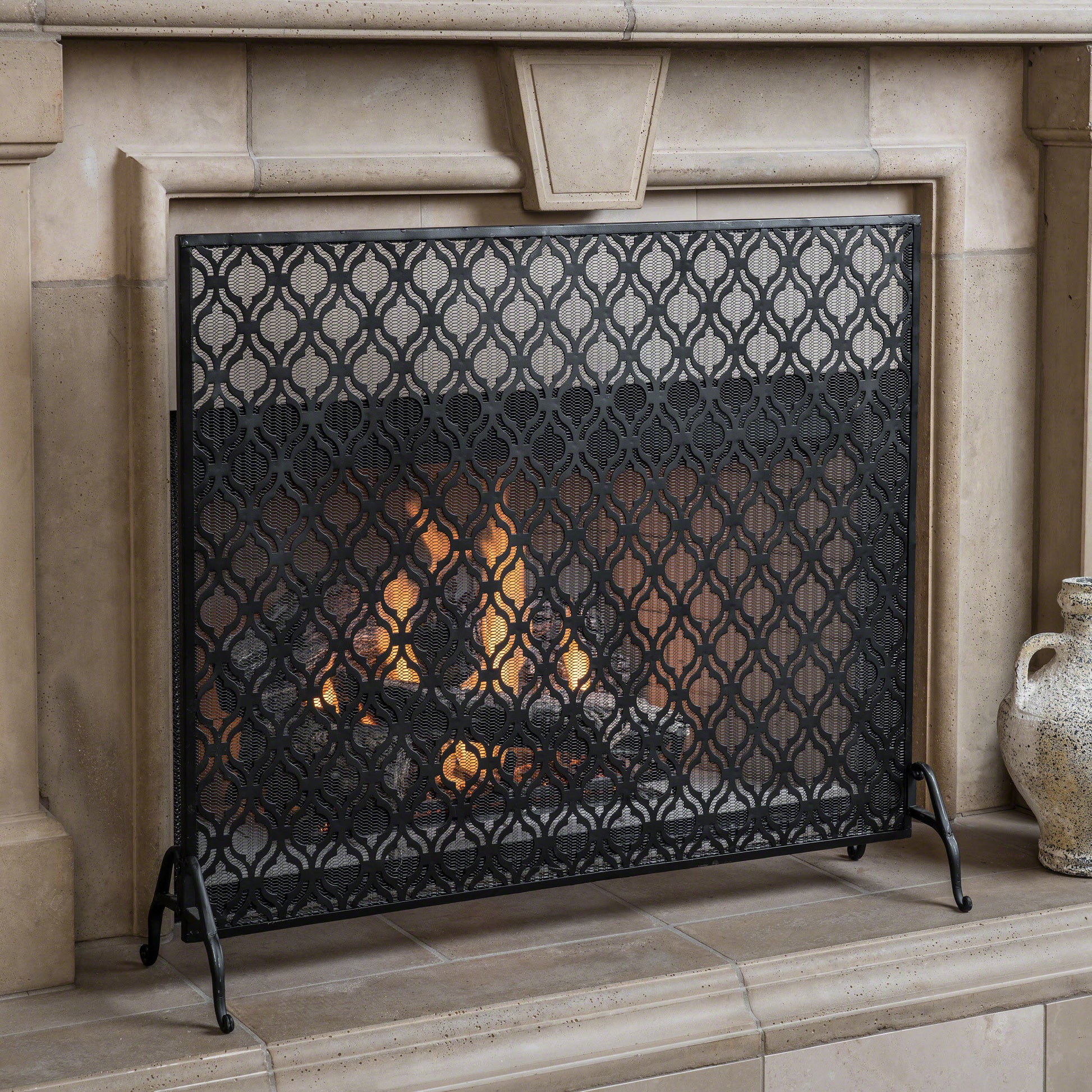 Black metal fireplace screen with ornate quatrefoil pattern