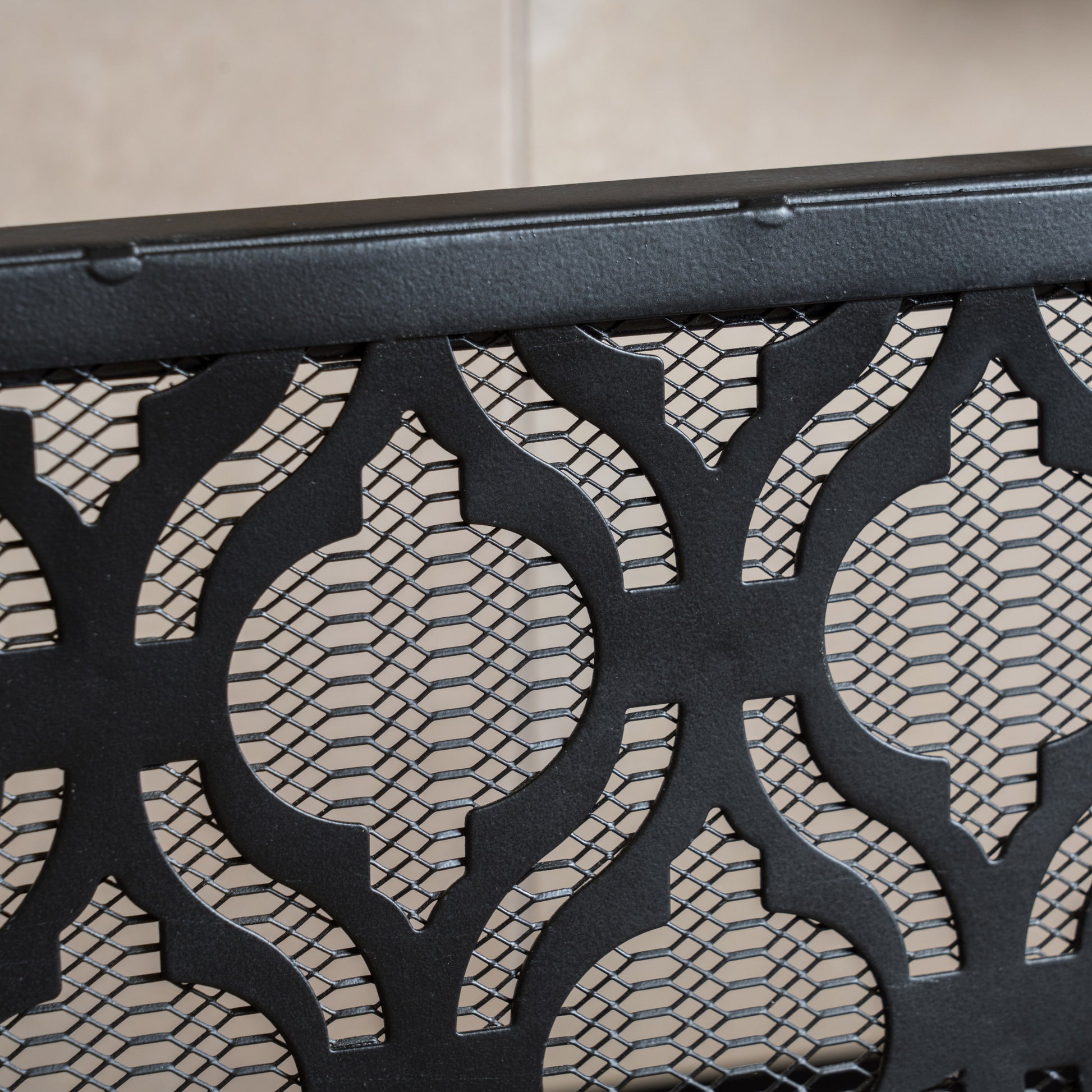Black ornate metal fireplace screen with intricate scrolling pattern