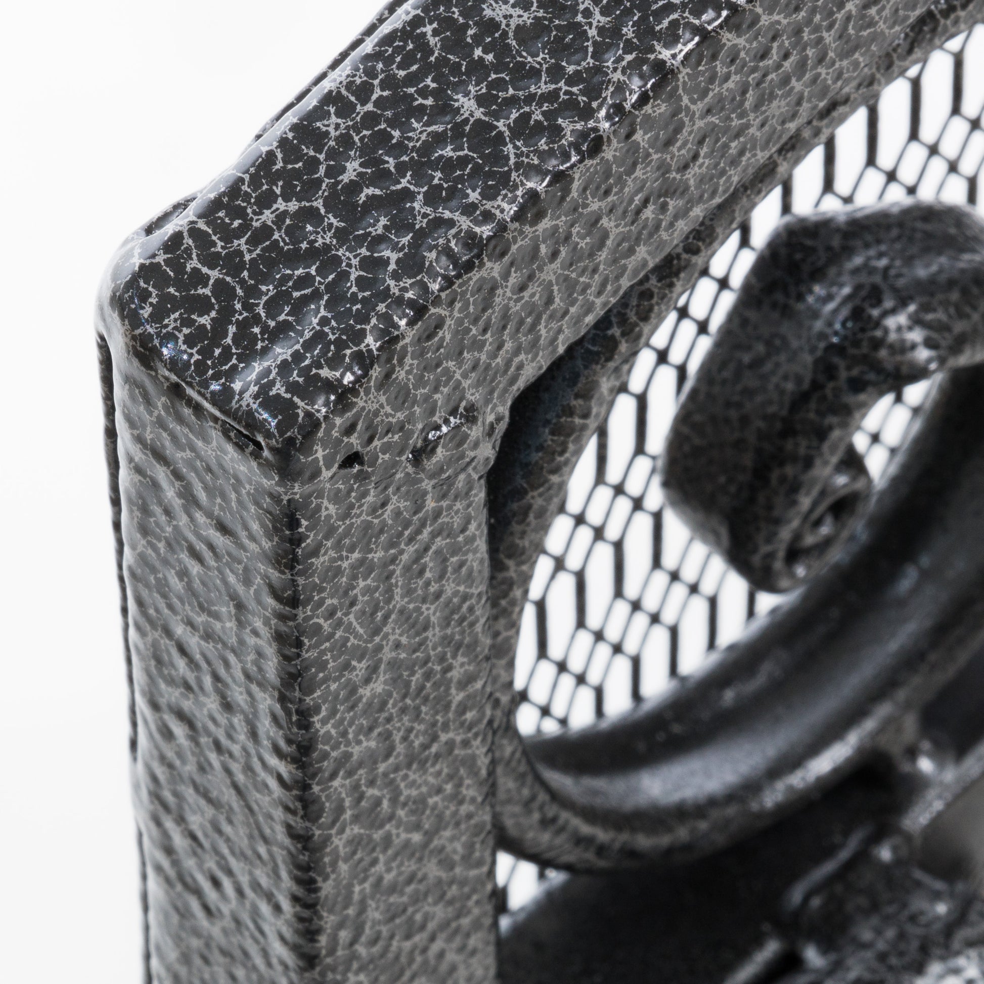 Closeup of a textured black metal scrollwork corner on a table